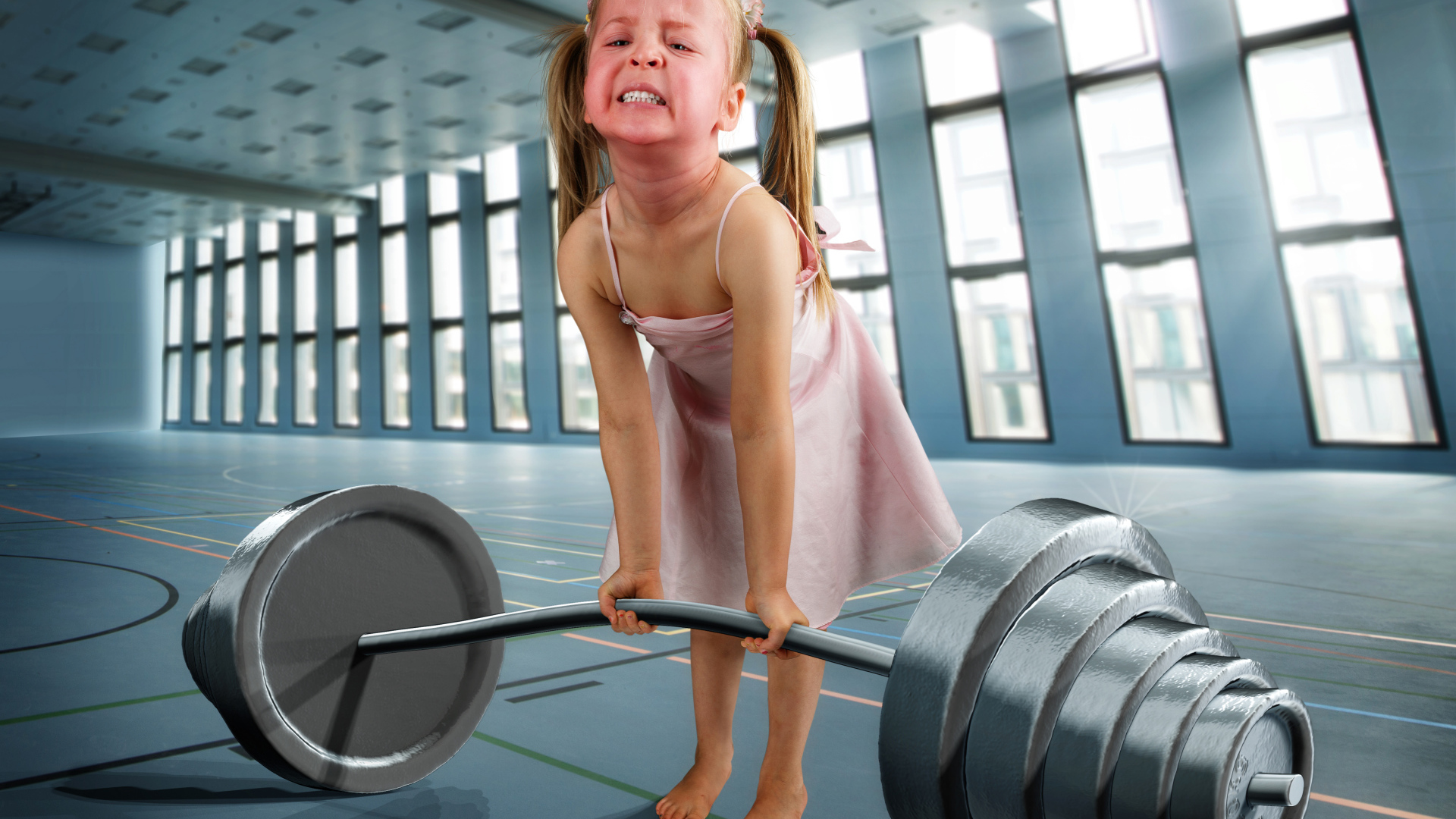 Смешная девочка пытается поднять тяжелую штангу