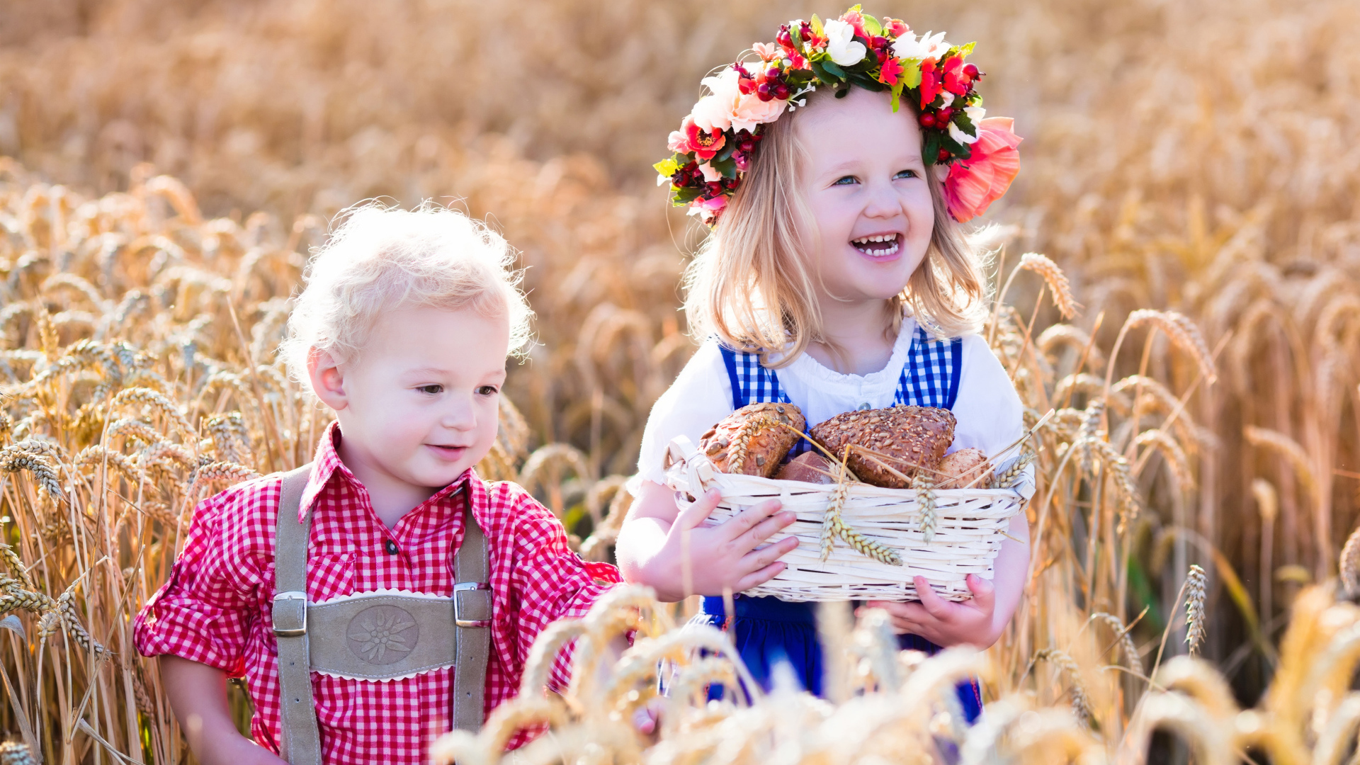 Маленькие мальчик и девочка на поле пшеницы с корзиной свежей выпечки