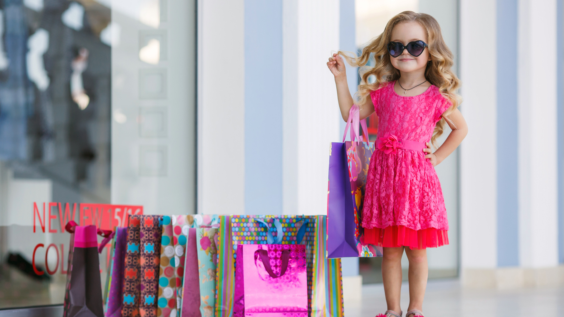 Маленькая модная девочка в красном платье с покупками