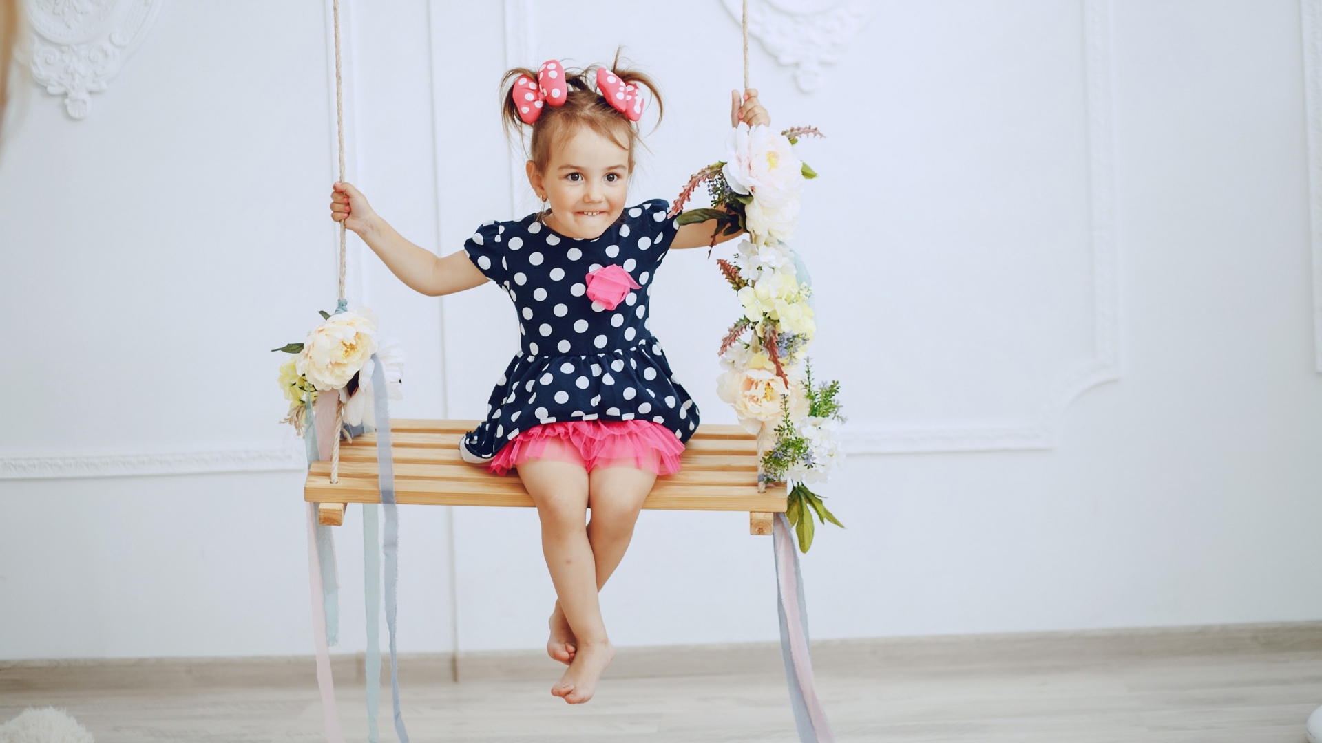 Маленькая забавная девочка в платье в горох  на качели