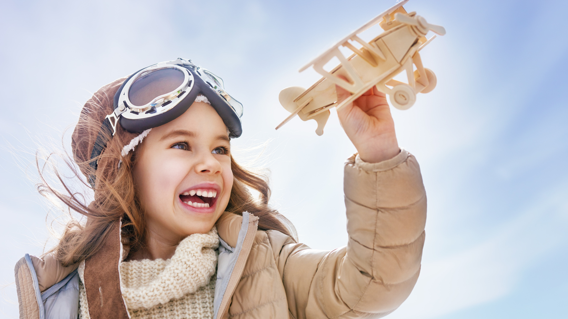 Маленькая улыбающаяся девочка с самолетом в руках 