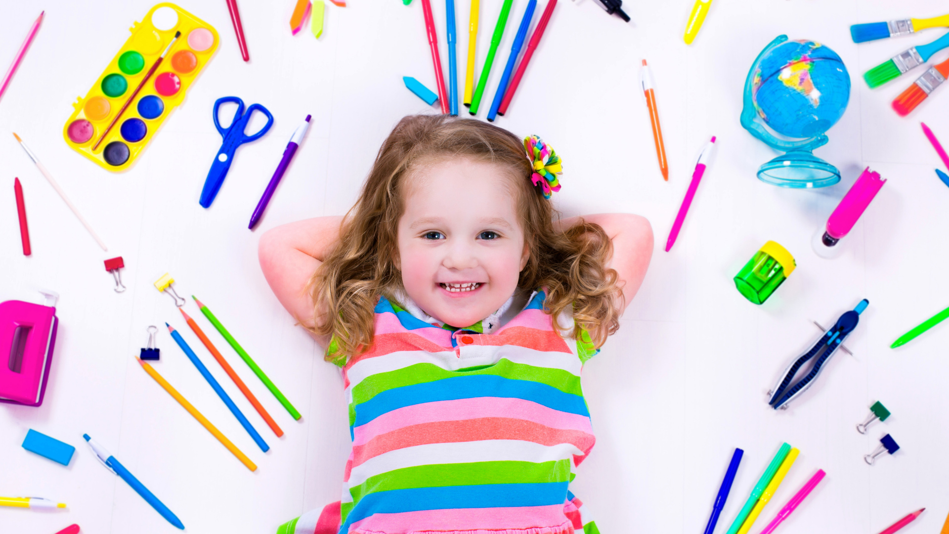 Маленькая улыбающаяся девочка со школьными принадлежностями