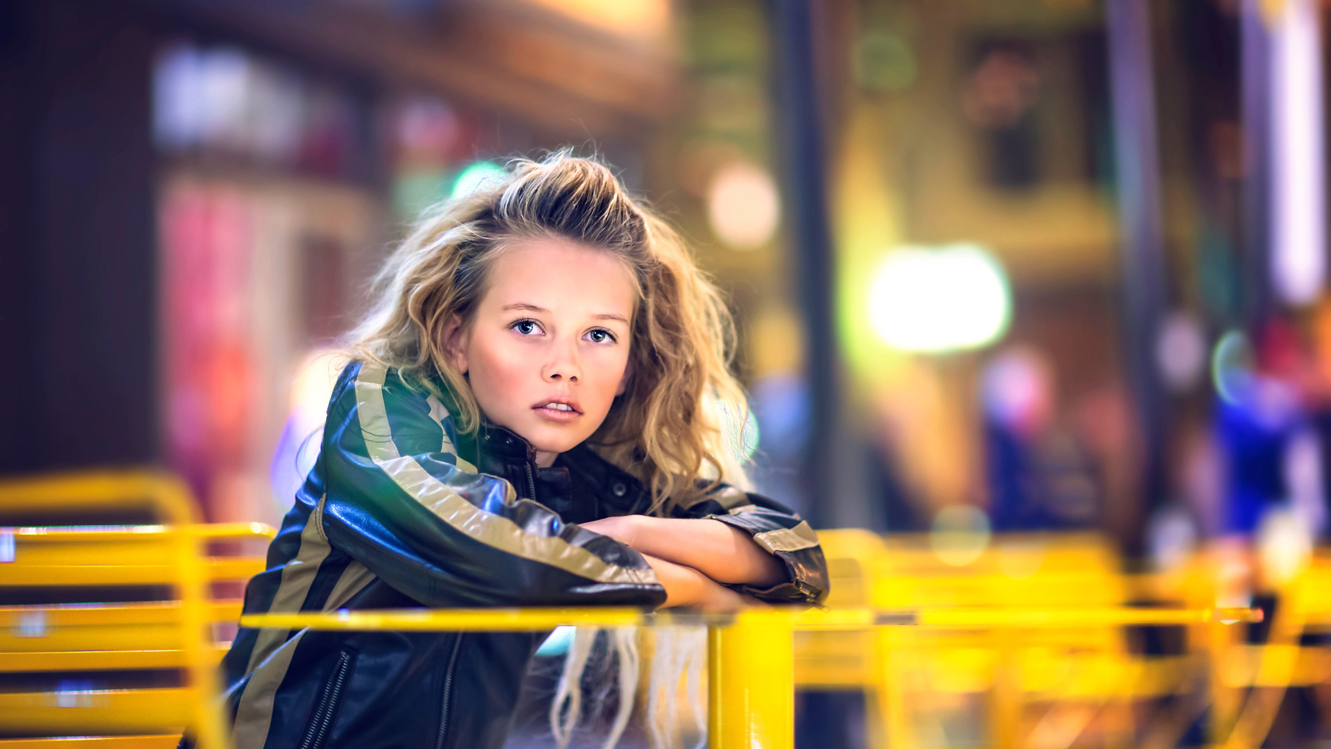 Длинноволосая девочка сидит на карусели