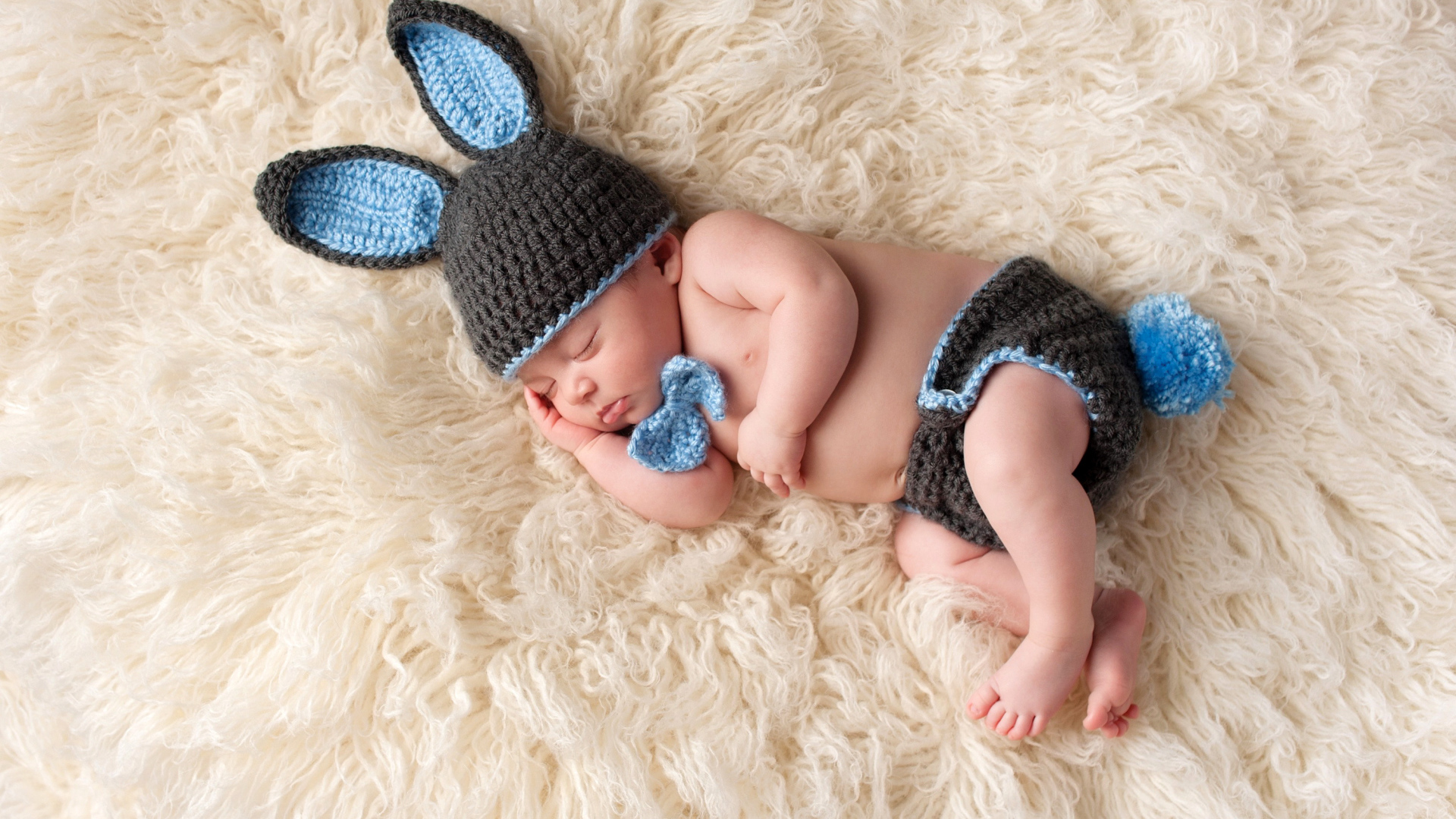 Спящий младенец в вязаном костюме зайца