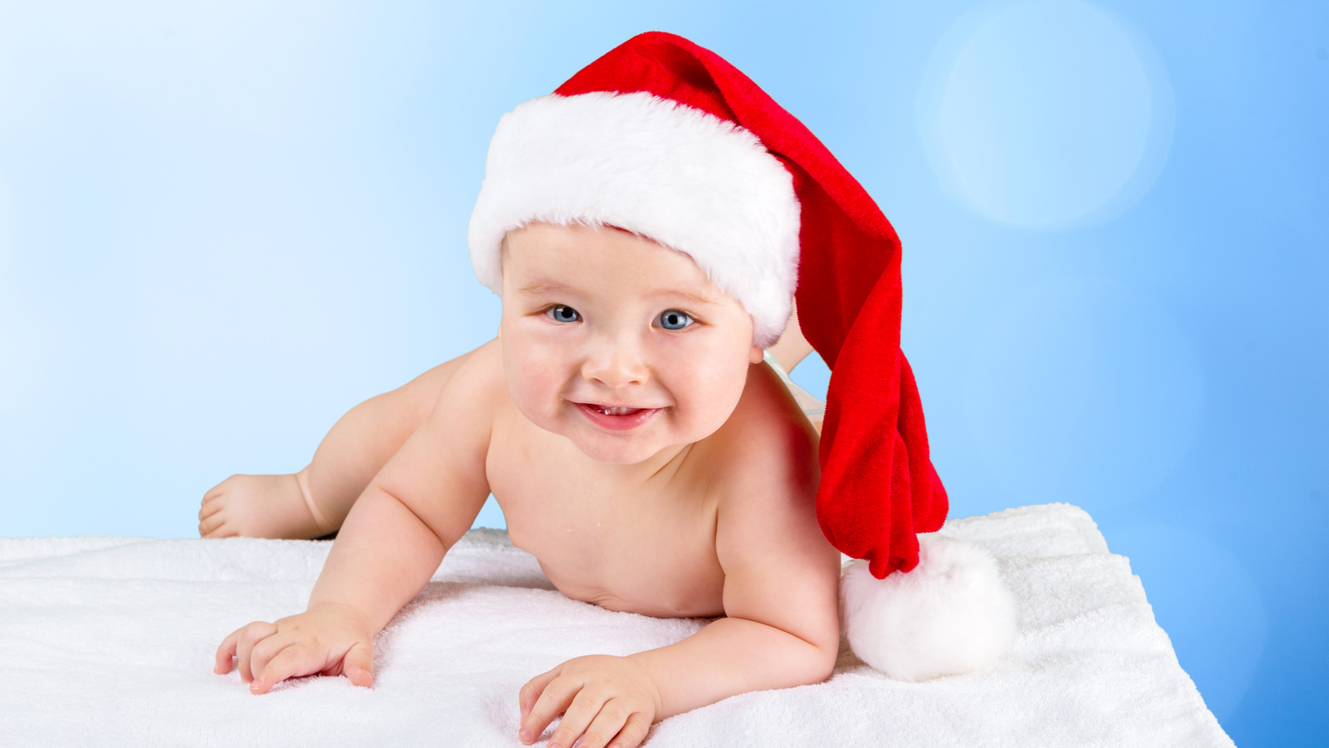 Улыбающийся грудной ребенок в новогодней шапке
