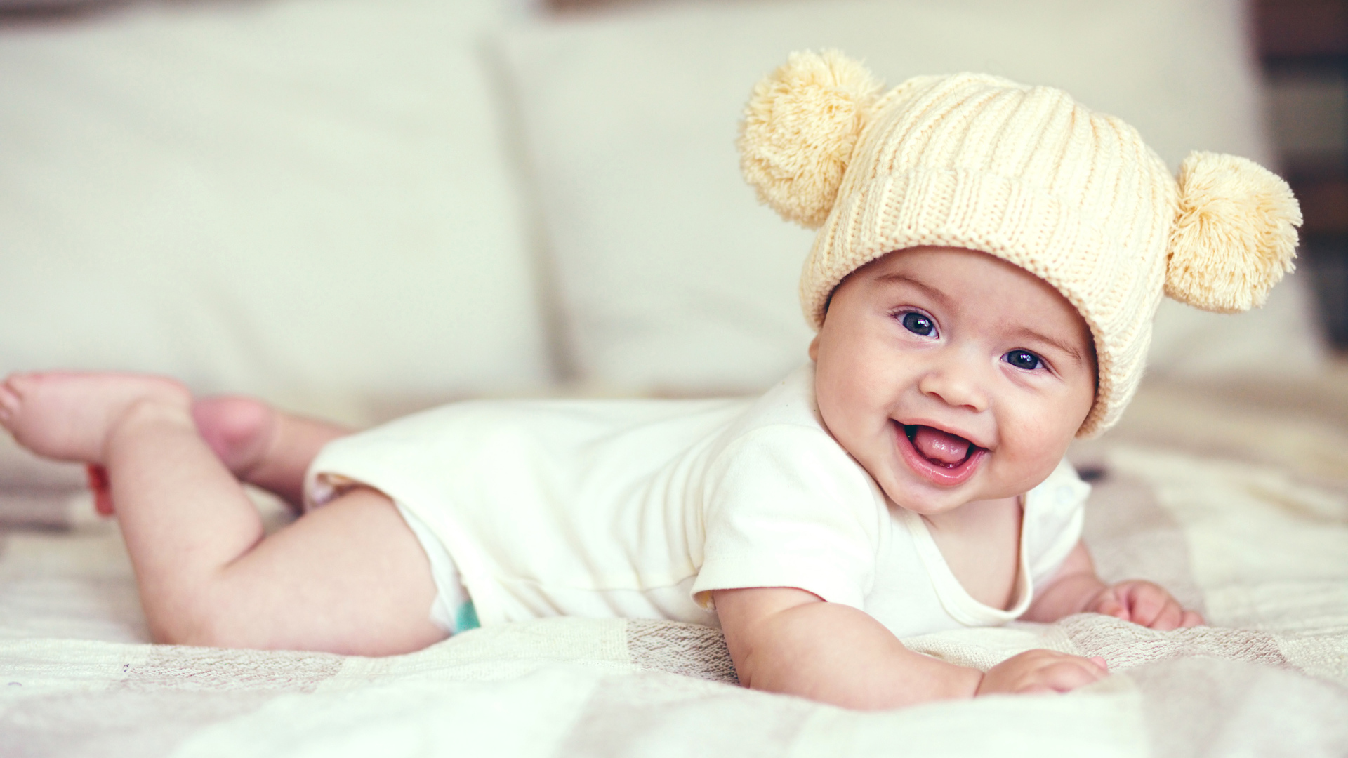 Улыбающийся грудной ребенок в забавной вязаной шапке