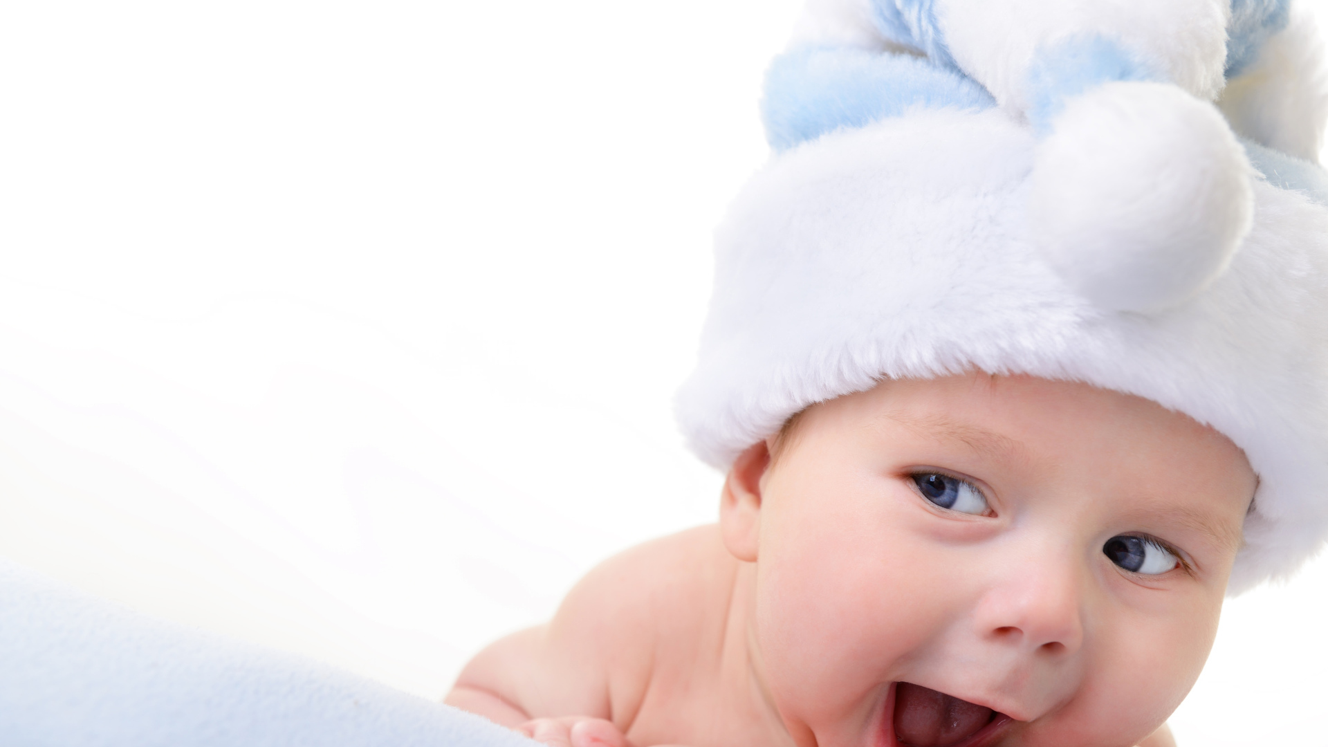 Улыбающийся грудной ребенок в голубой новогодней шапке