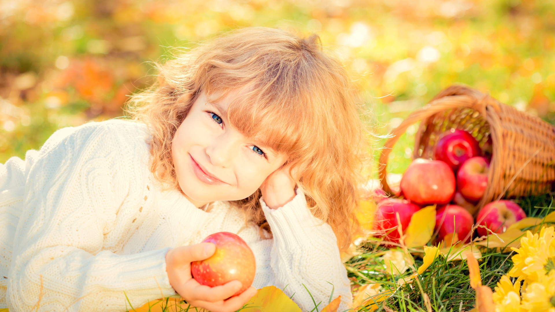 Улыбающаяся рыжеволосая девочка с корзиной красных яблок