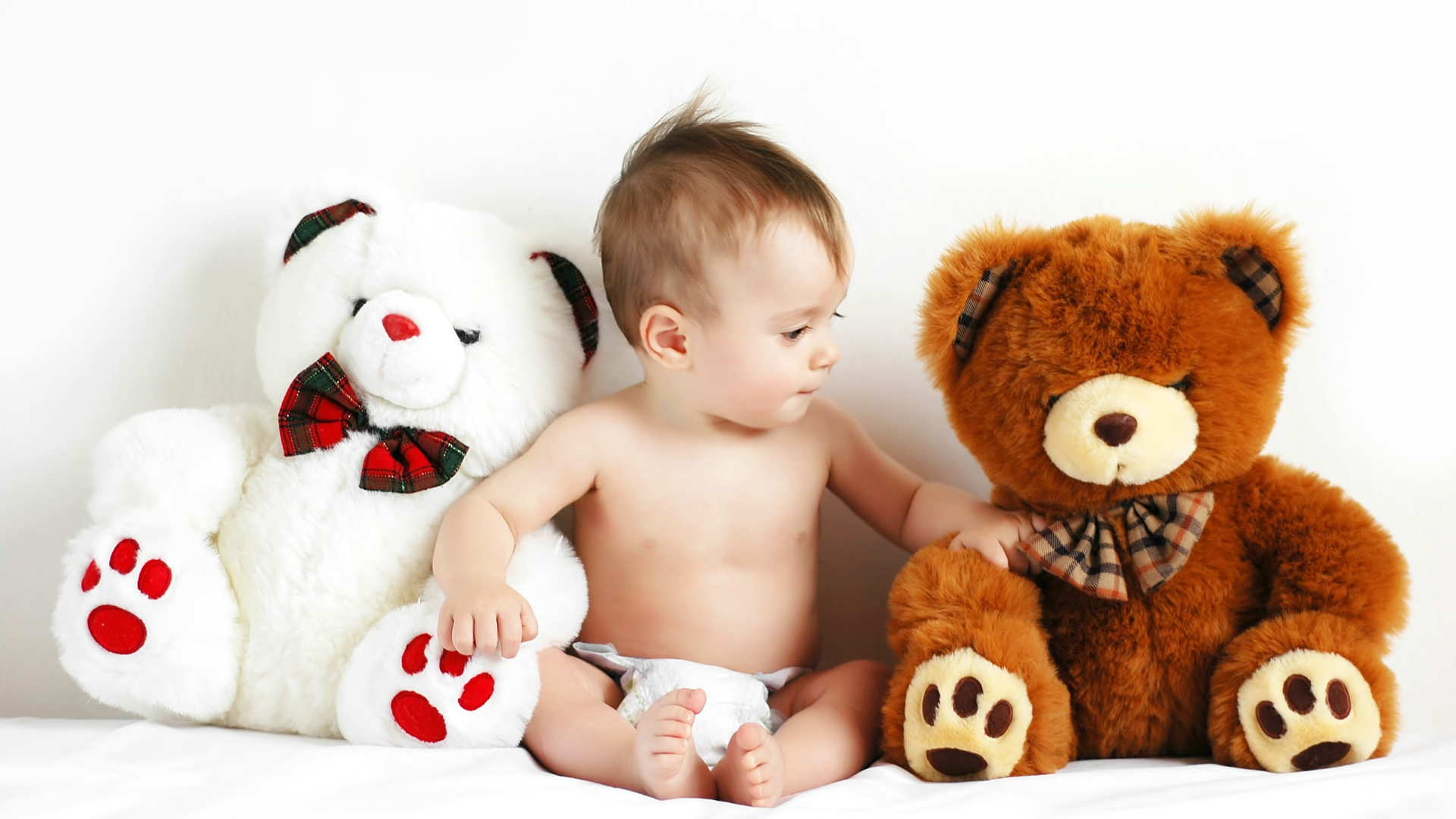 Младенец сидит с двумя большими плюшевыми медведями