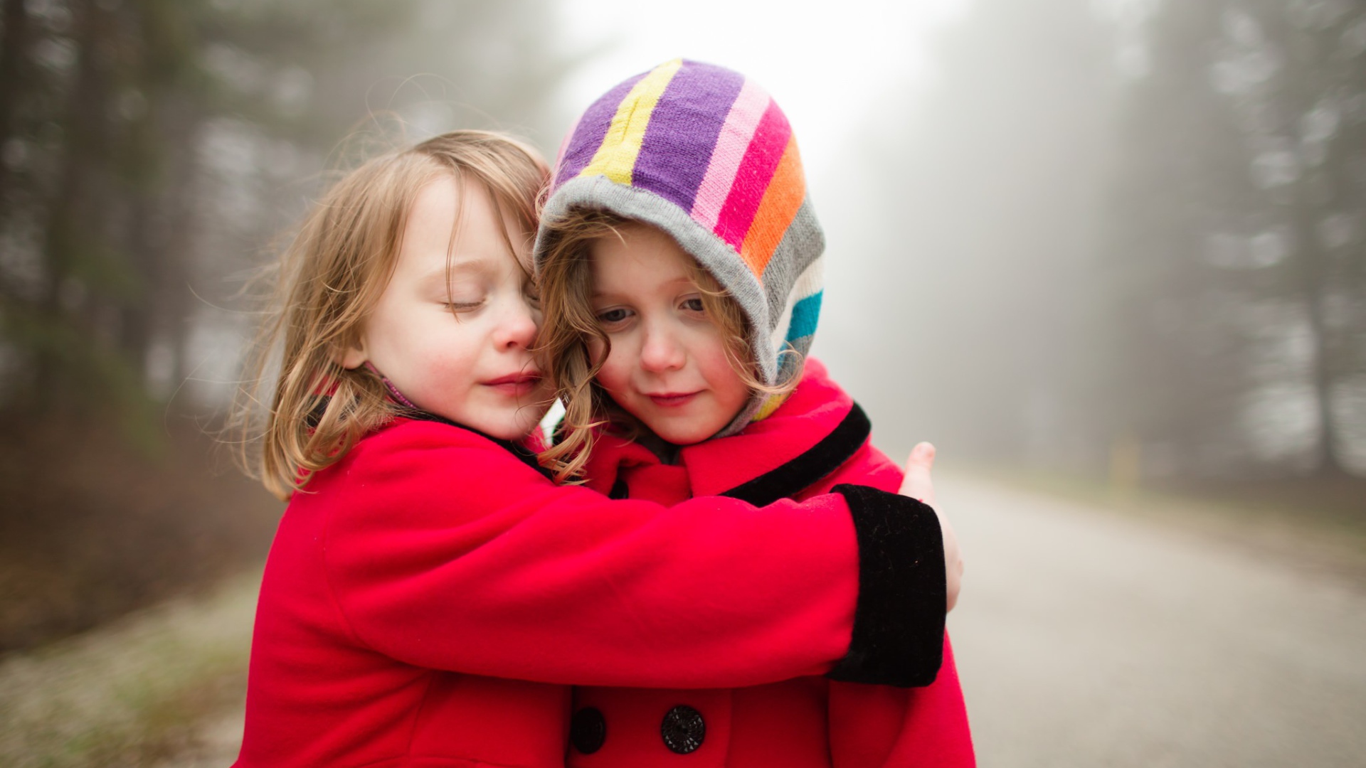 Две маленькие девочки обнимают друг друга 