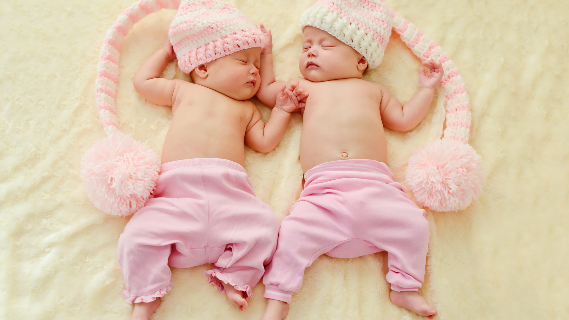 Два спящих грудных ребенка в розовых костюмах