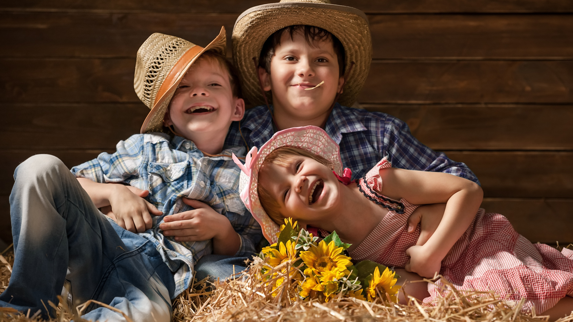 Два улыбающихся мальчика и девочка в соломенных  шляпах