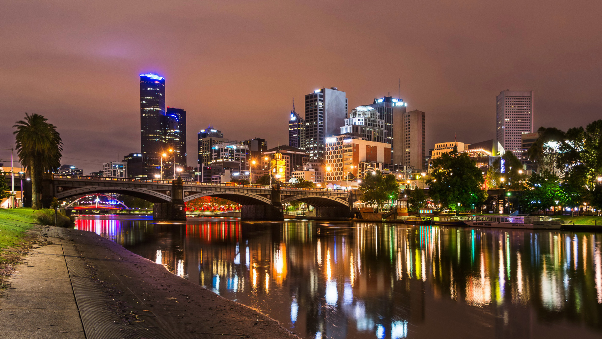 The lights of the night skyscrapers of the city of Melbourne are reflected in the water channel. Australia