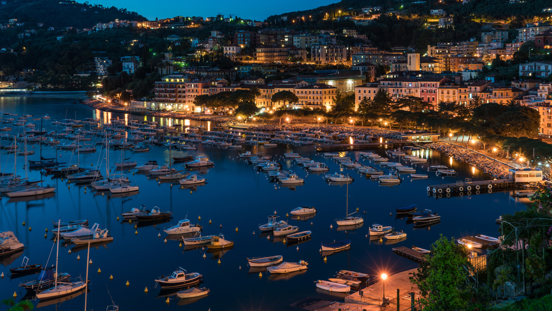 Панорама ночного города и лодки на причале у побережья, Лигурия. Италия