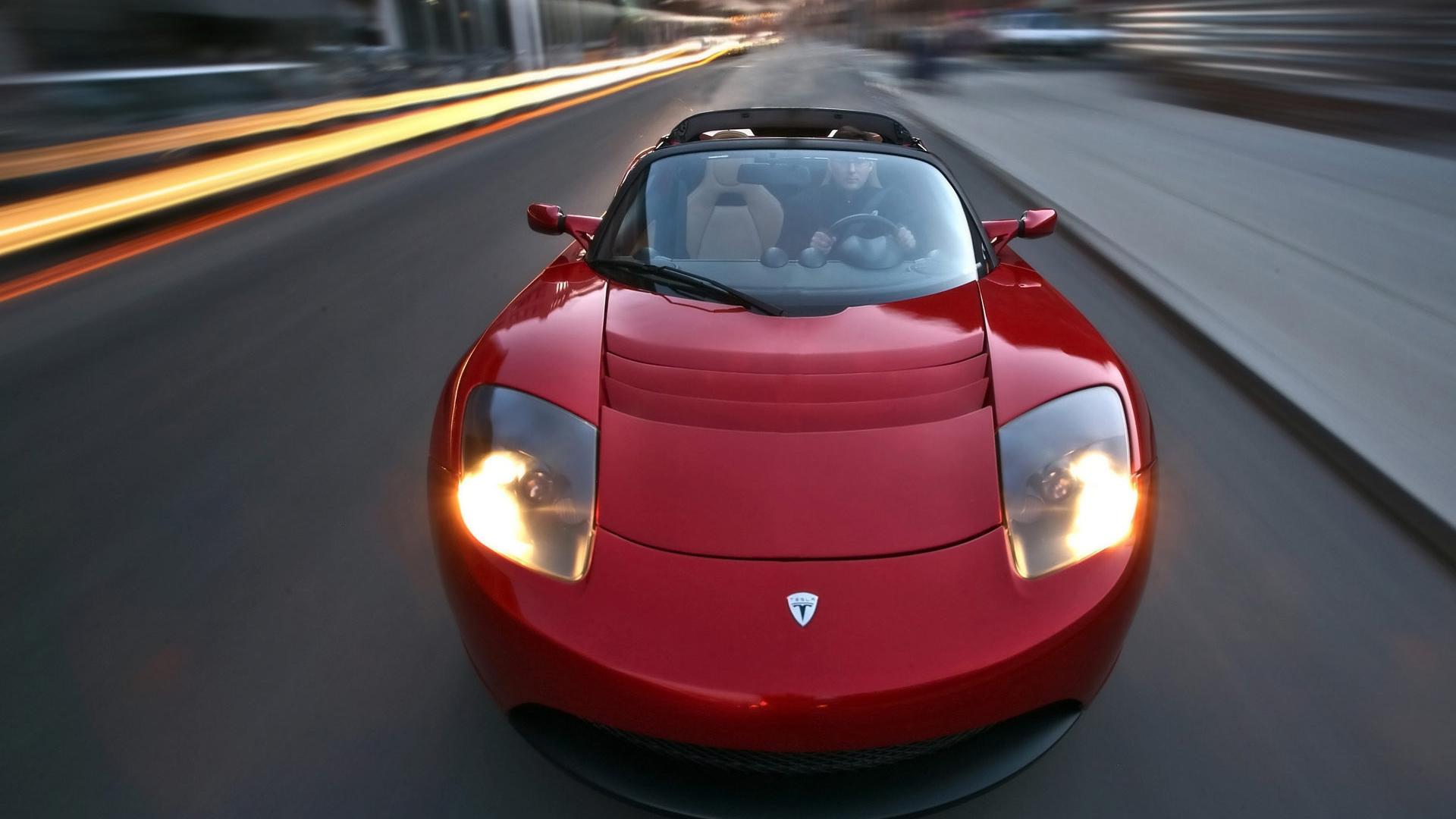 Красный электромобиль Tesla Roadster на трассе 