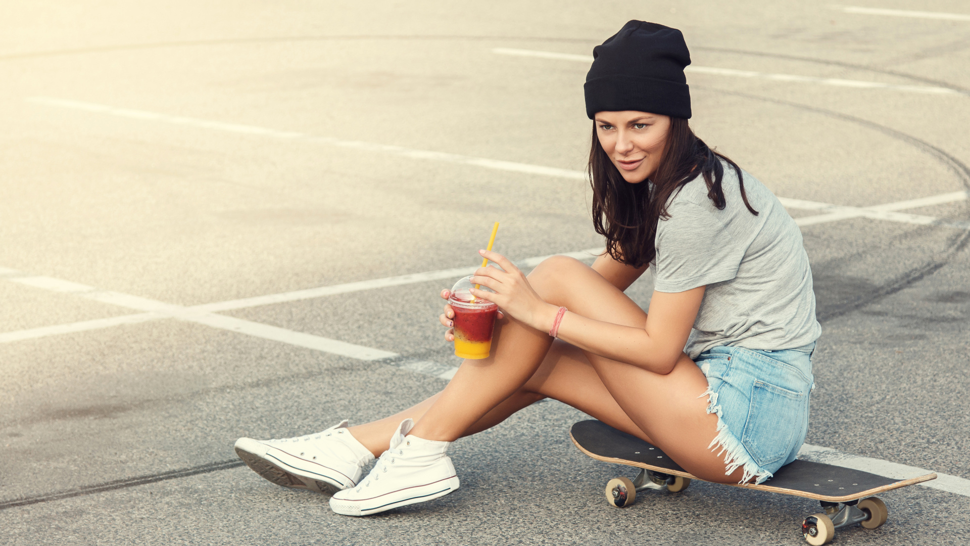 Спортивная девушка сидит на доске для скейтборда 