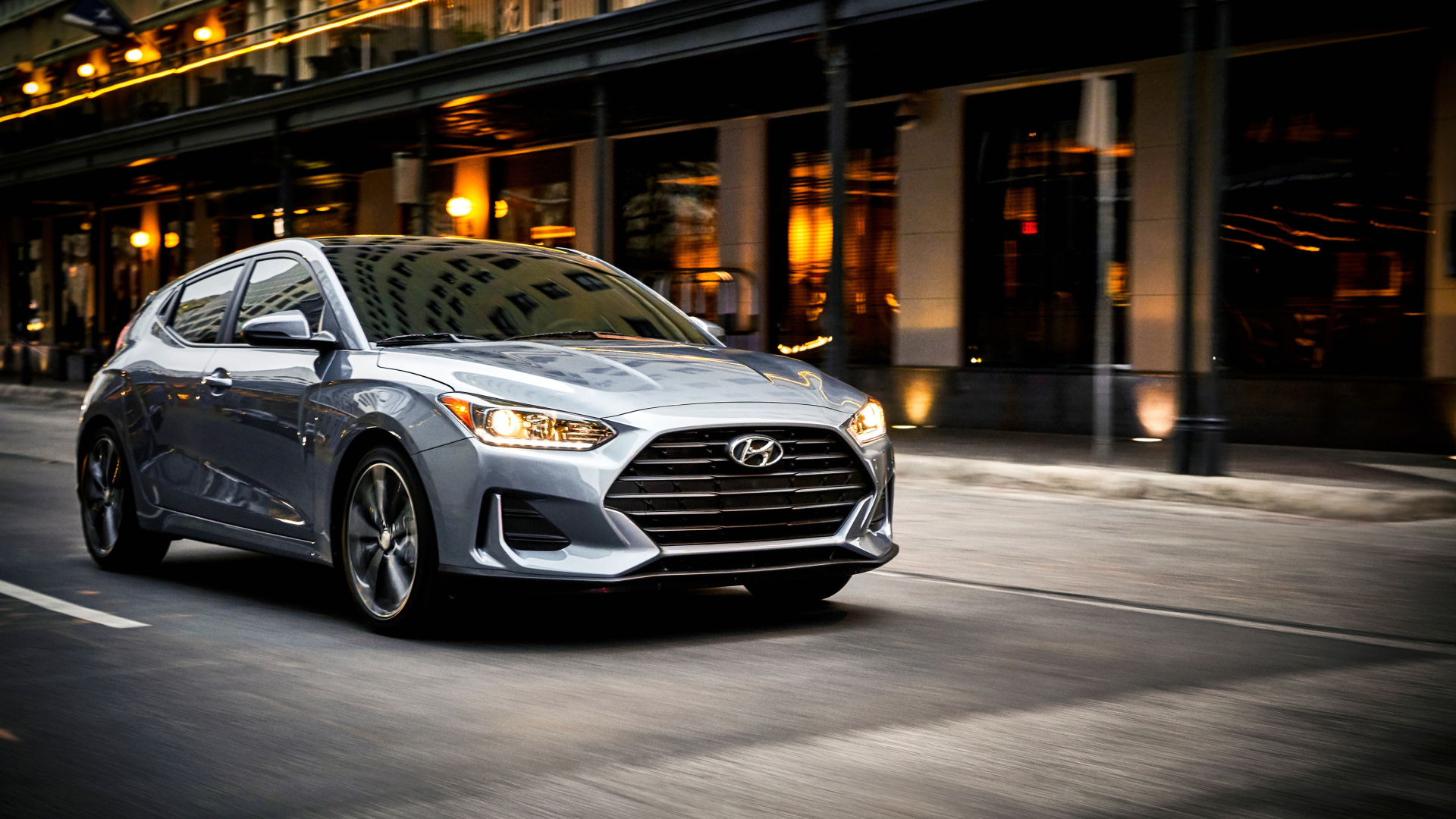 Серебристый автомобиль Hyundai Veloster, 2019 с  включенными фарами 