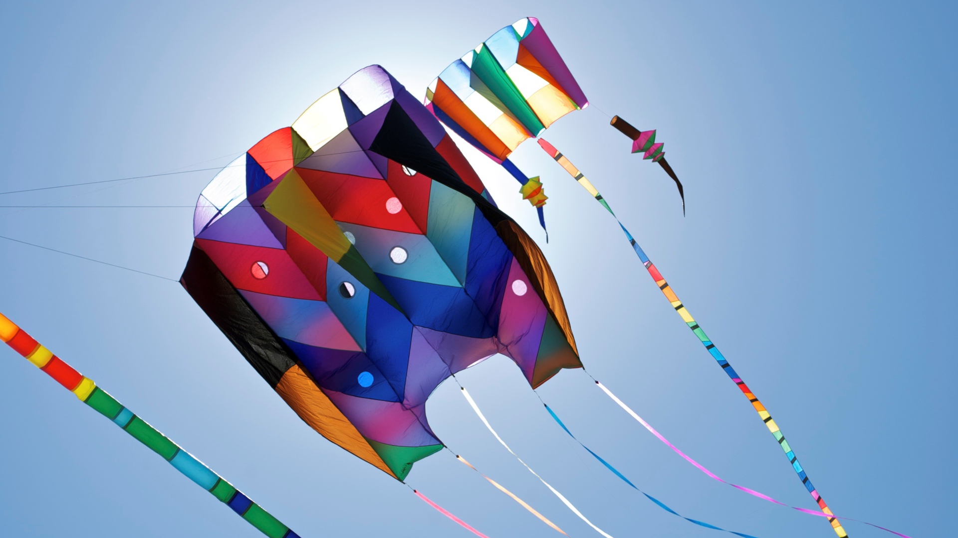 Разноцветный воздушный змей в голубом небе в лучах солнца