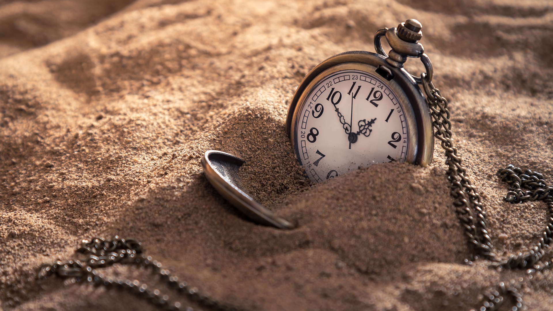 Карманные часы на цепочке в песке 