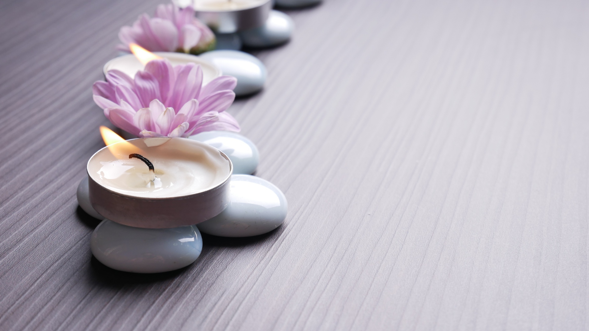 Камни с ароматическими свечами и цветами хризантемы