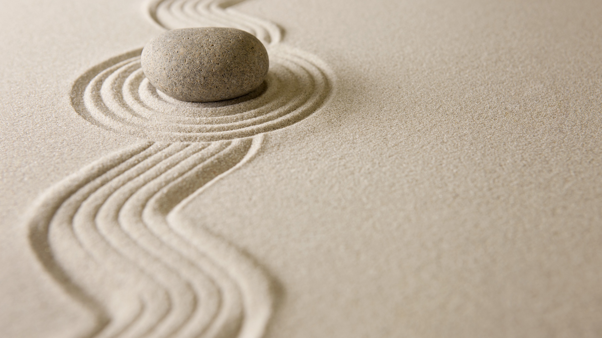 Камень лежит на рисунке на песке, дзен