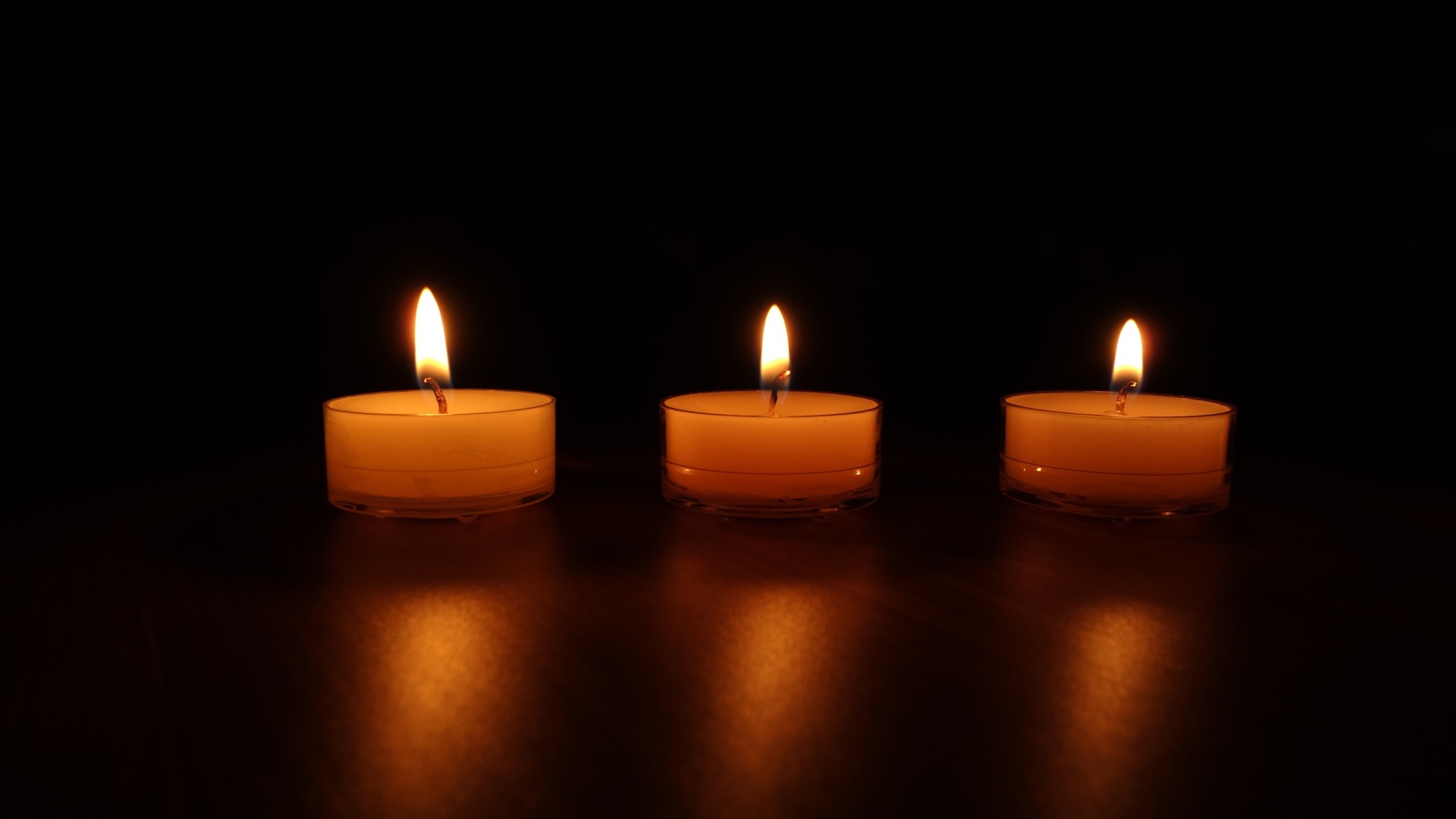 Три зажженные свечи на черном фоне