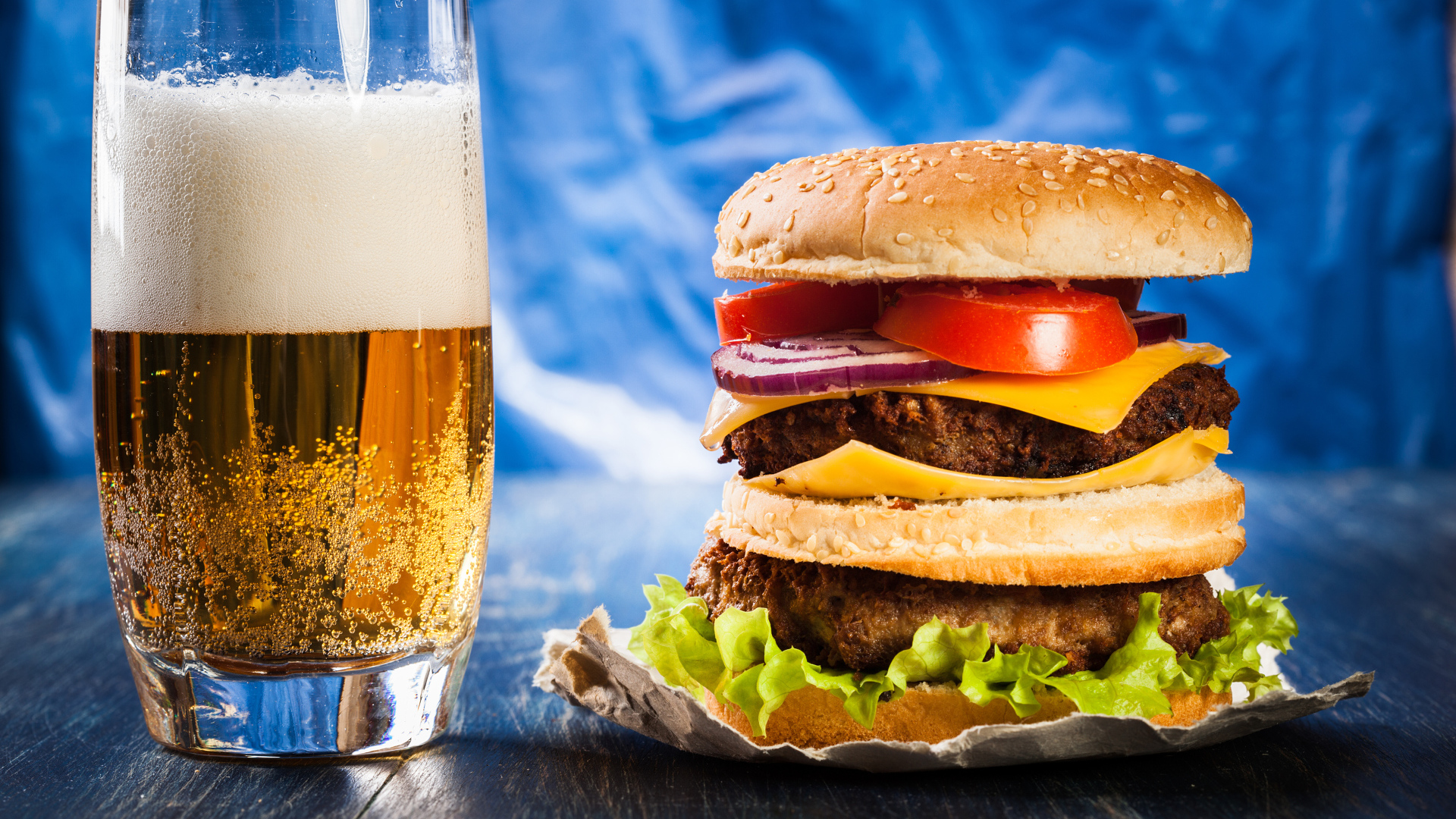 Стакан пива с гамбургером на столе