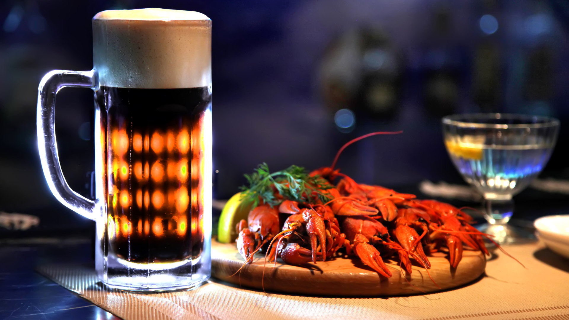 Бокал пива с вареными раками на столе