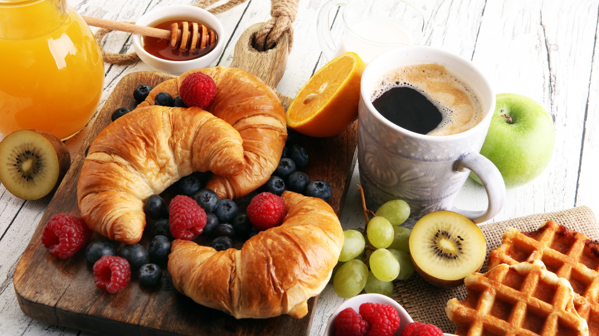 Круассаны с ягодами, на столе с кофе, медом и вафлями