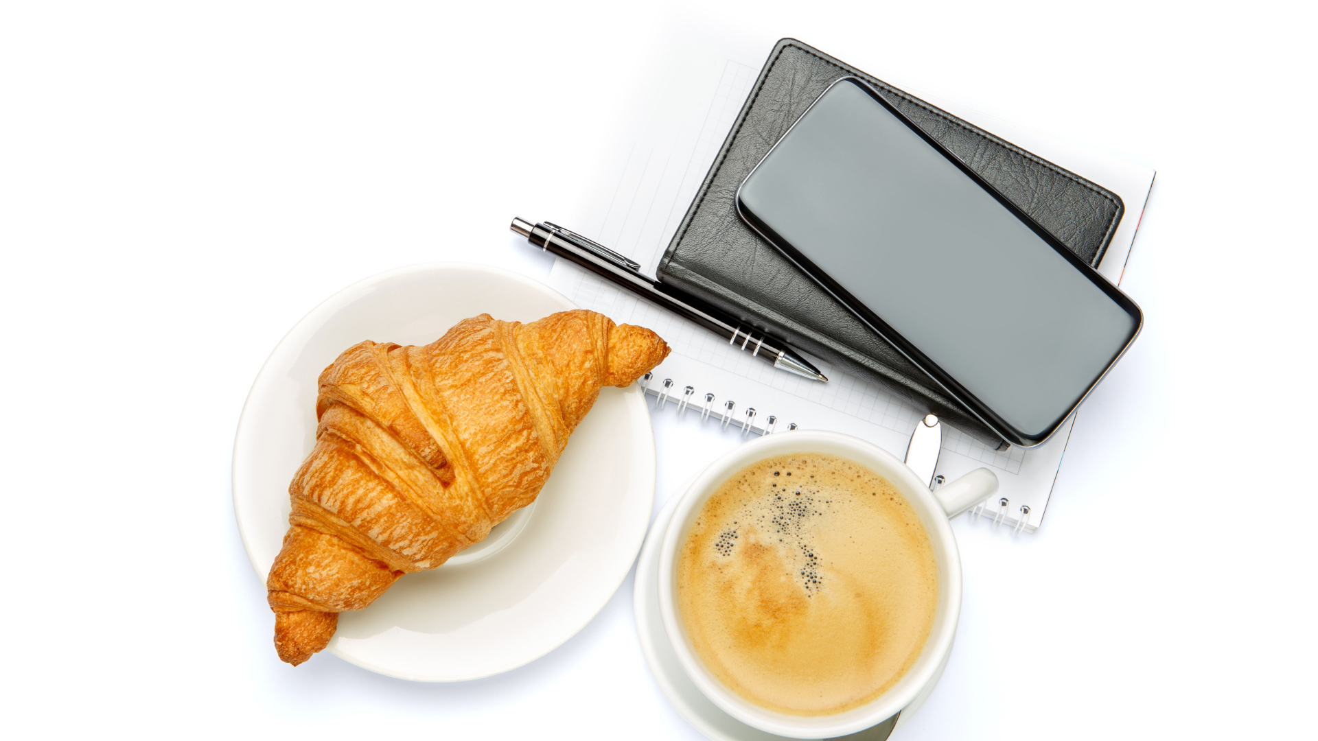 Чашка кофе, круассан, блонтон и смартфон на белом 