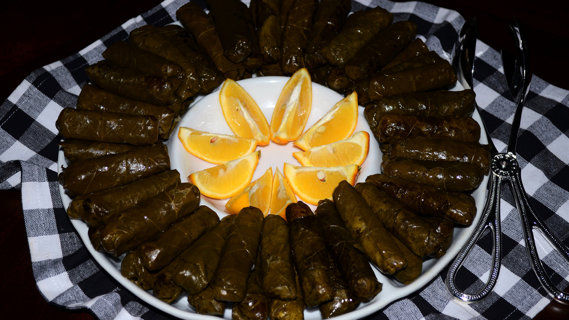 Долма на большом блюде с кусочками апельсина 