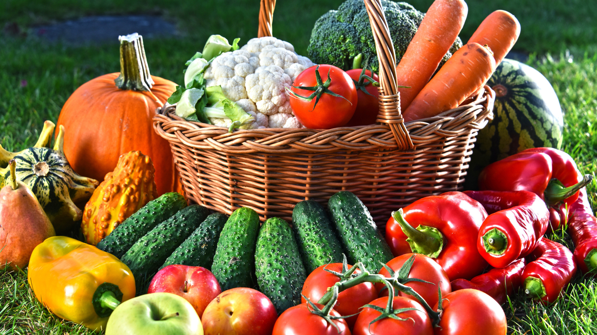Свежие овощи и фрукты в корзине на зеленой траве