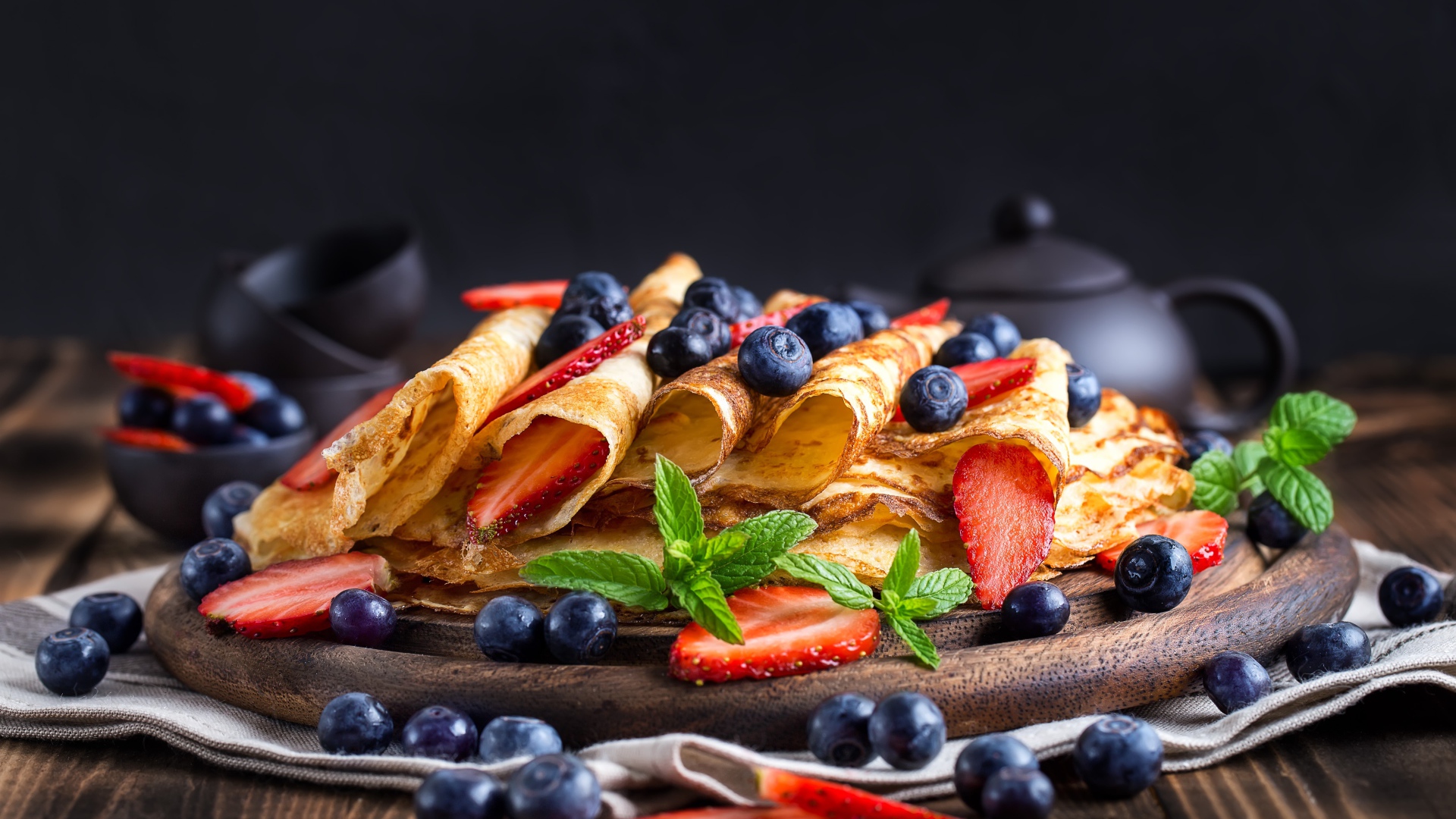 Блинчики с ягодами черники и клубники на столе