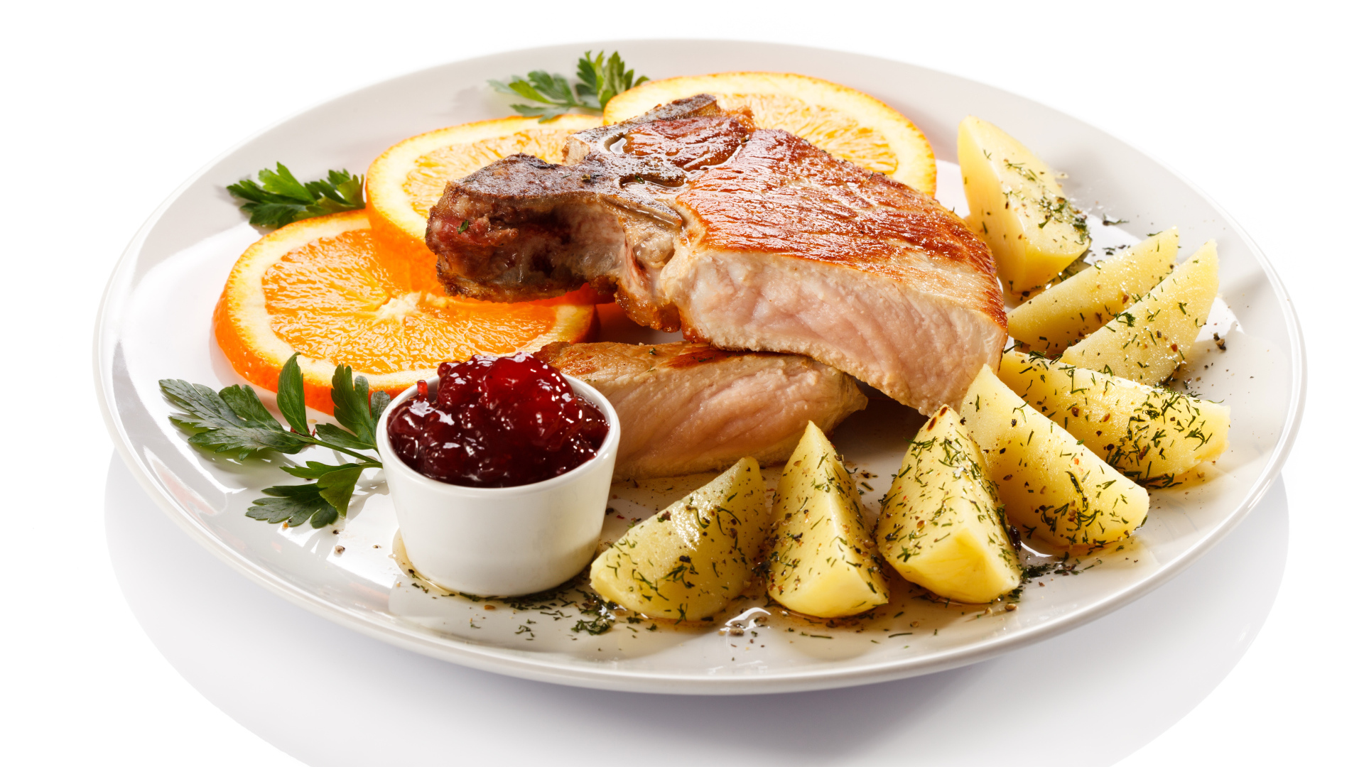 Картофель с мясом и кусочками апельсина на тарелке