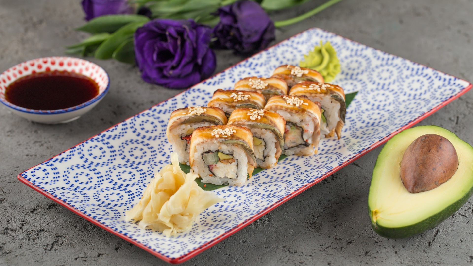 Роллы с авокадо и соевым соусом на столе с цветами 