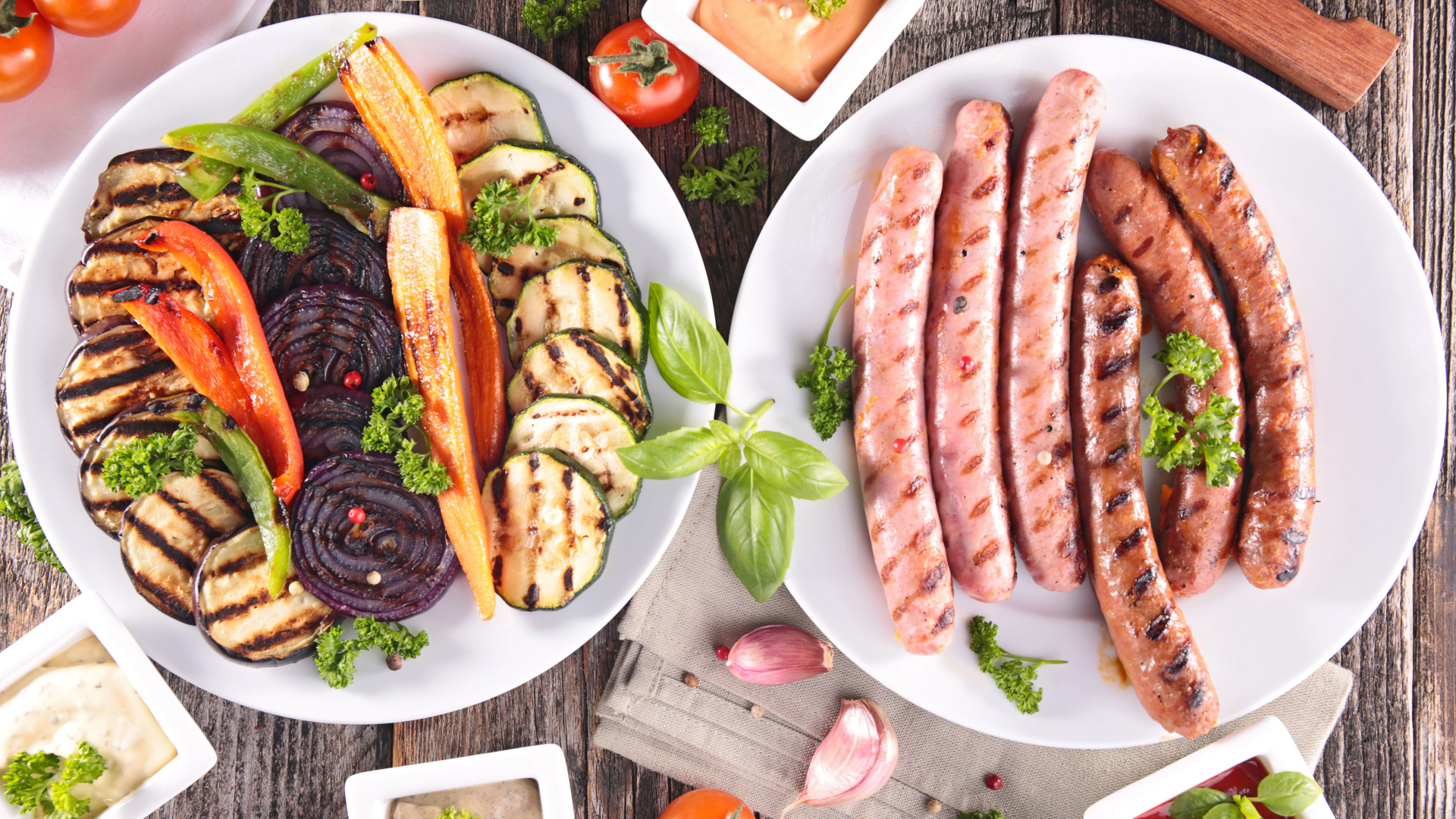 Овощи и сосиски гриль на столе с соусом