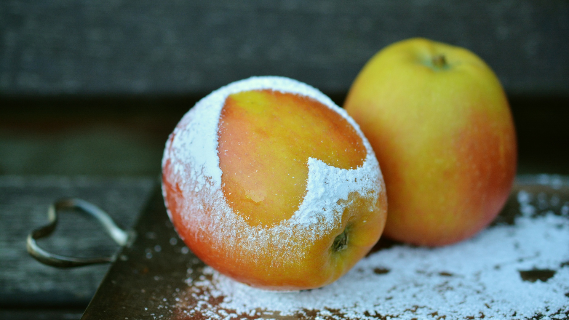 Спелое яблоко с сердцем из сахарной пудры на столе 