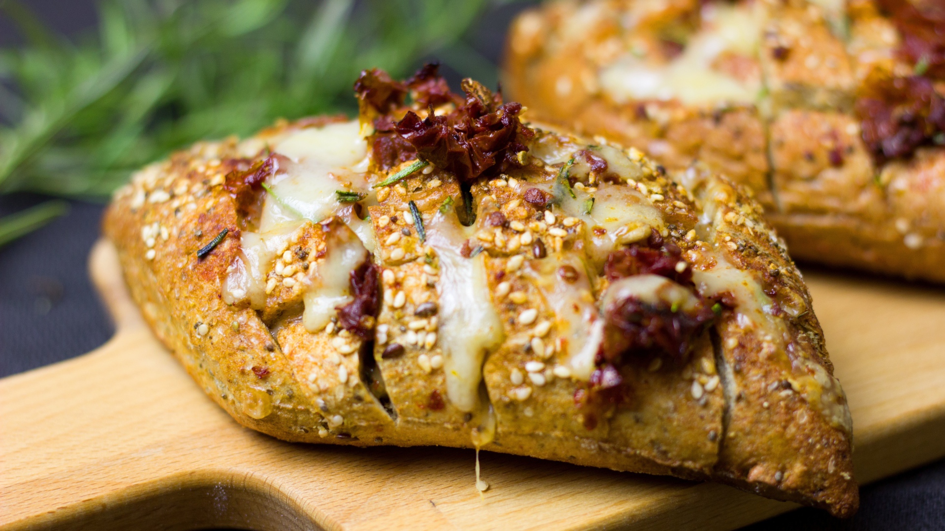 Булочка с кунжутом и сыром на разделочной доске 