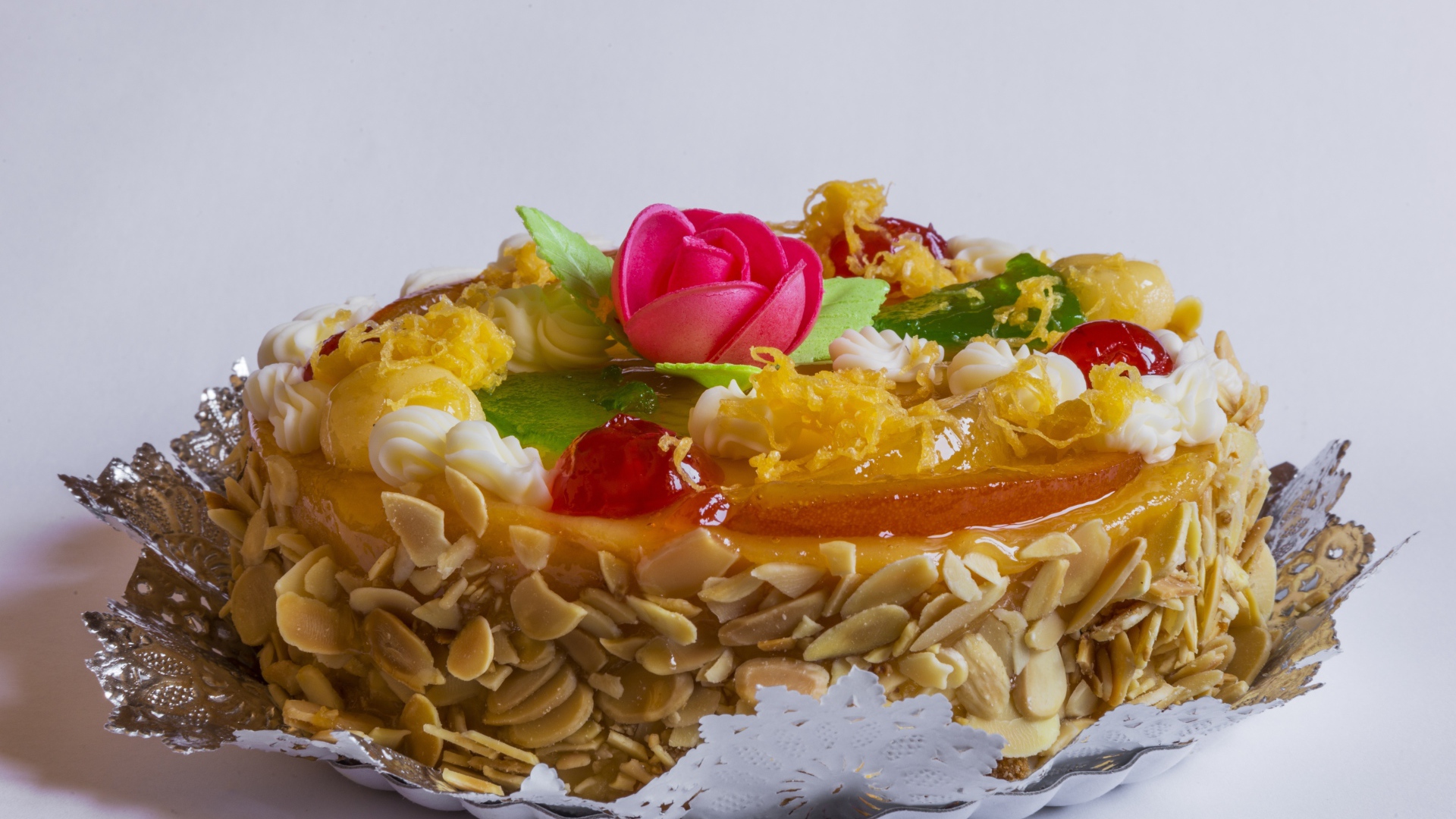 Красивый торт с кремом и ягодами украшен розовым цветком