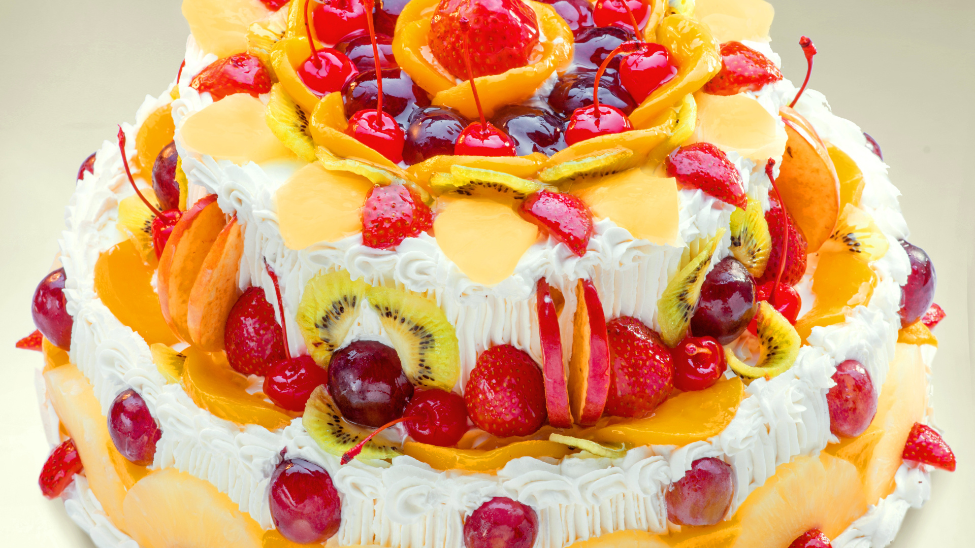 Красиво украшенный ягодами и фруктами торт с кремом