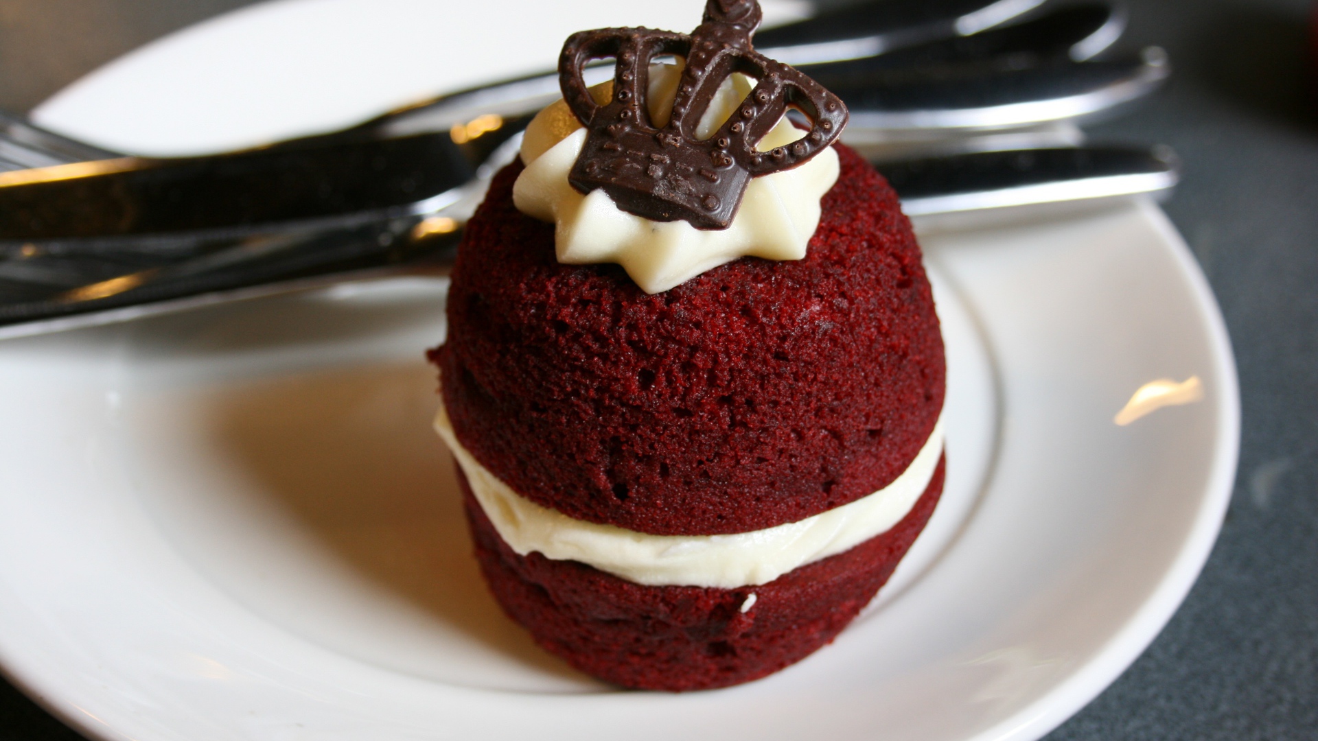 Пирожное с кремом и украшением из шоколада на белой тарелке