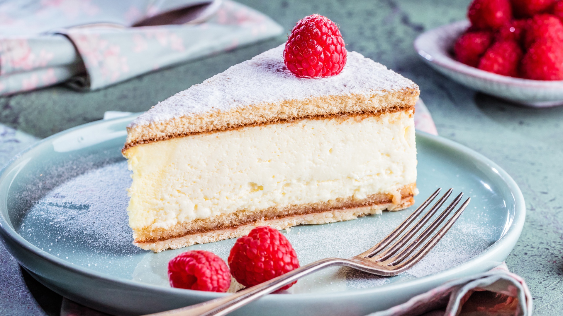 Чизкейк с сахарной пудрой и ягодами малины на тарелке