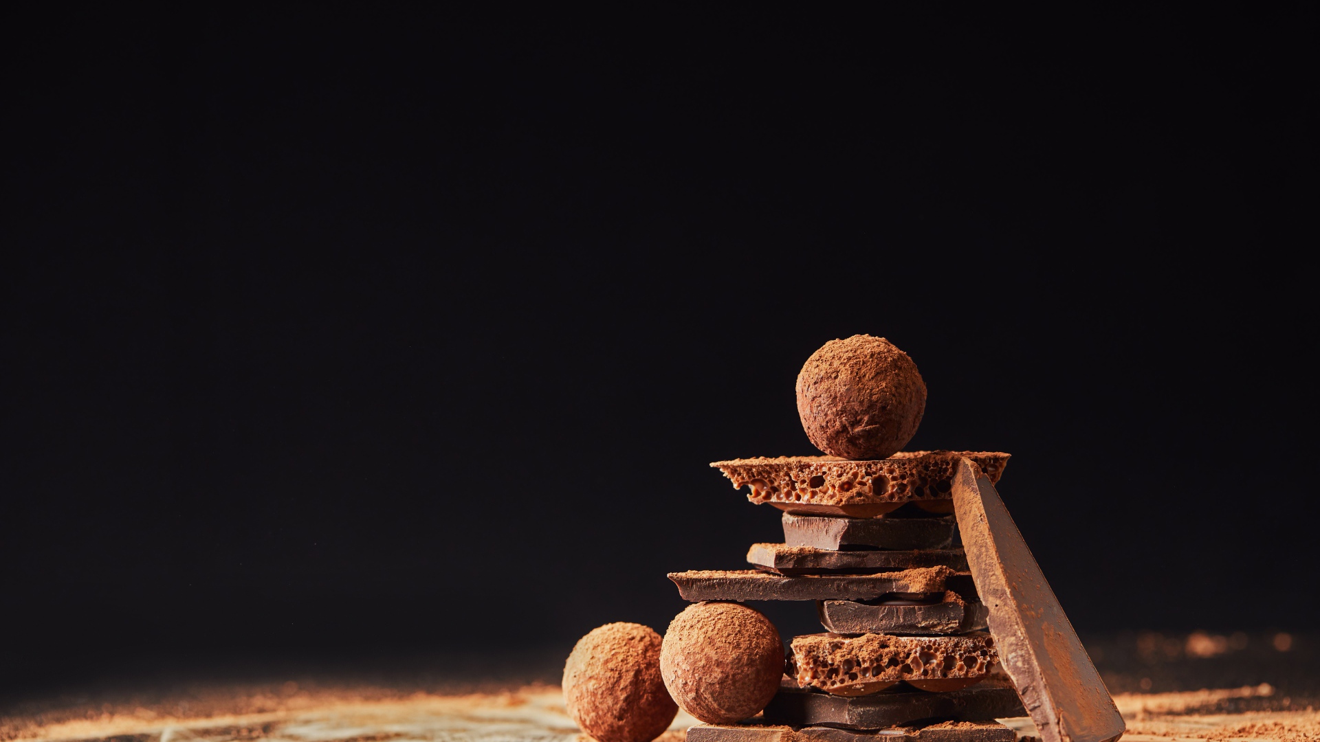 Шоколадные шарики и кусочки шоколада на черном фоне