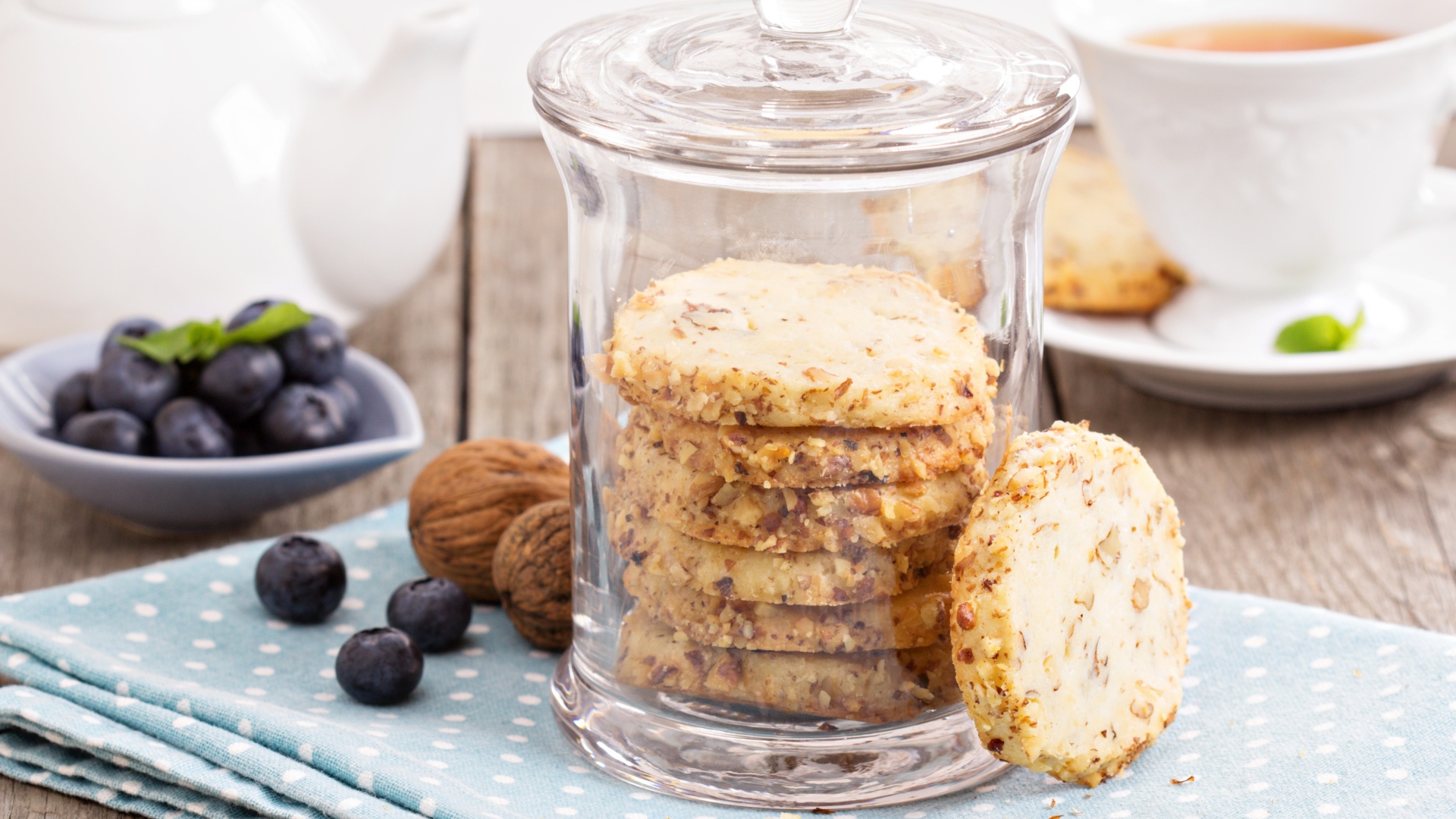 Печенье в стеклянной банке на столе с орехами и черникой