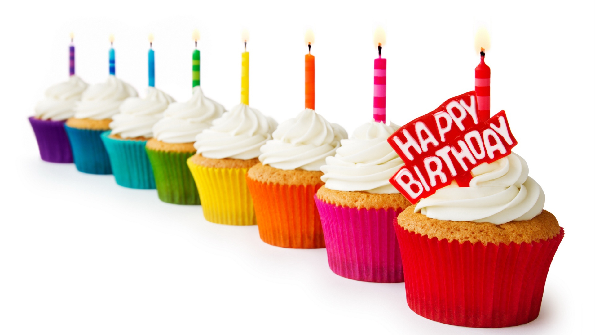 Кексы со свечами и кремом на день рождения на белом фоне 