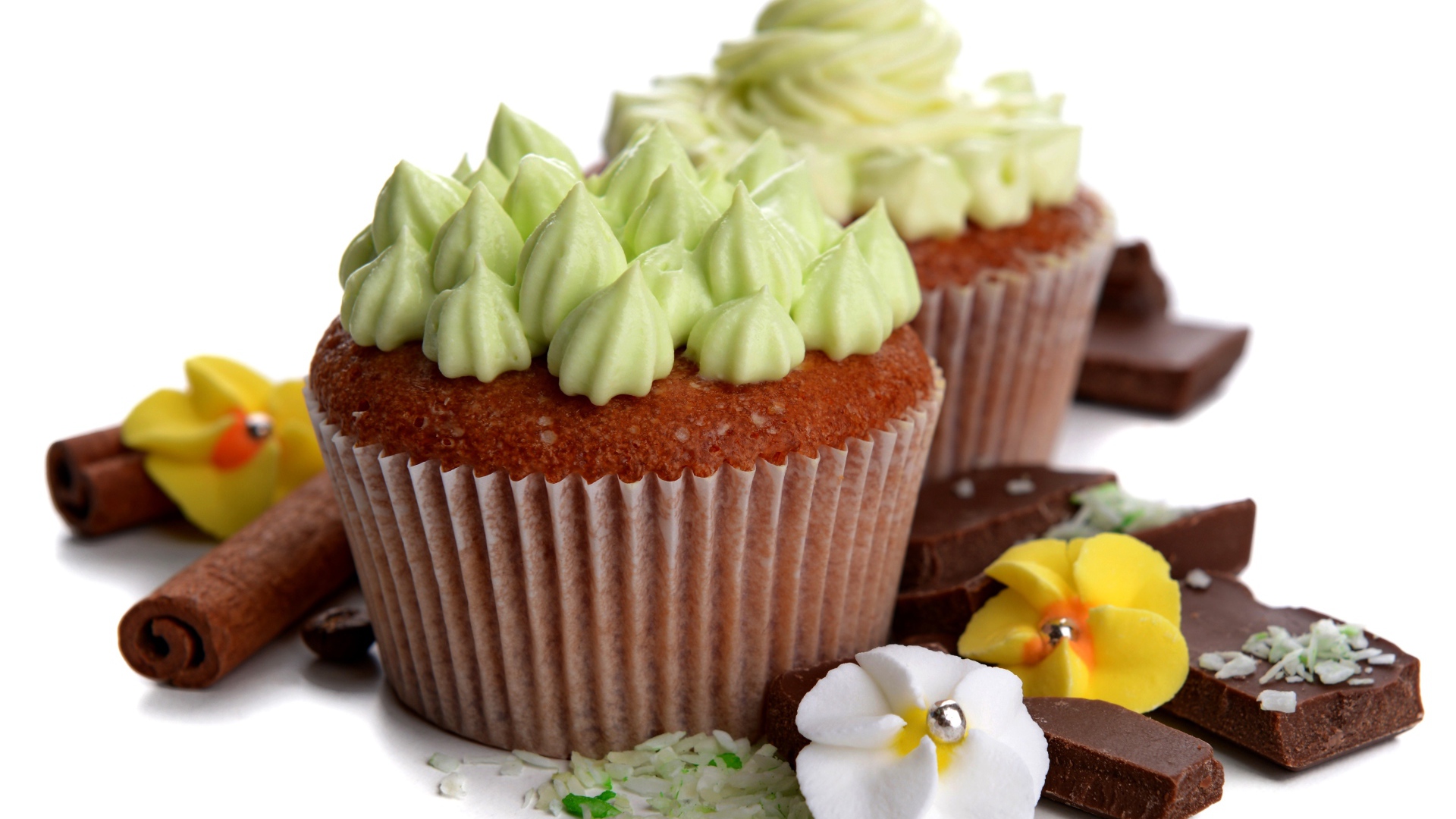 Кексы с кремом, шоколадом и корицей на белом фоне