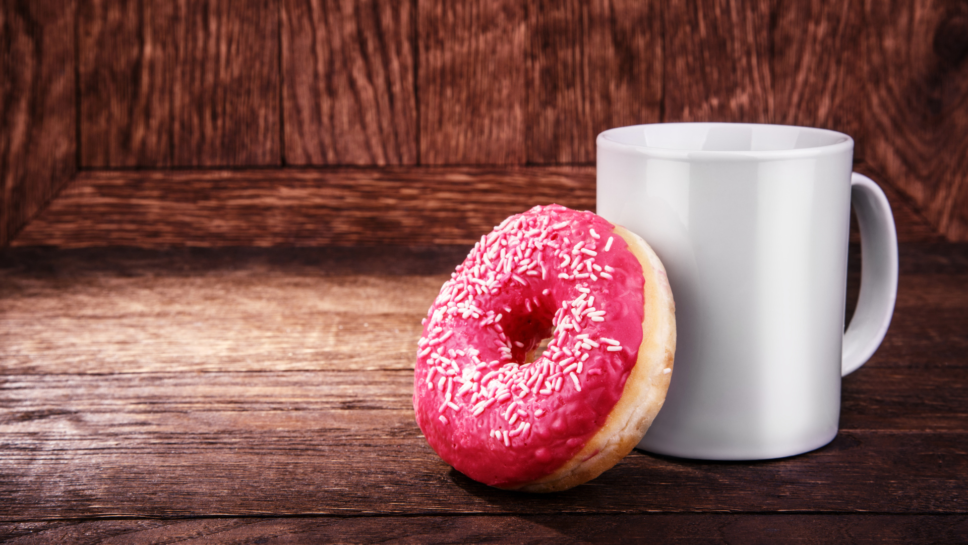 Пончик с белой кружкой на деревянном столе
