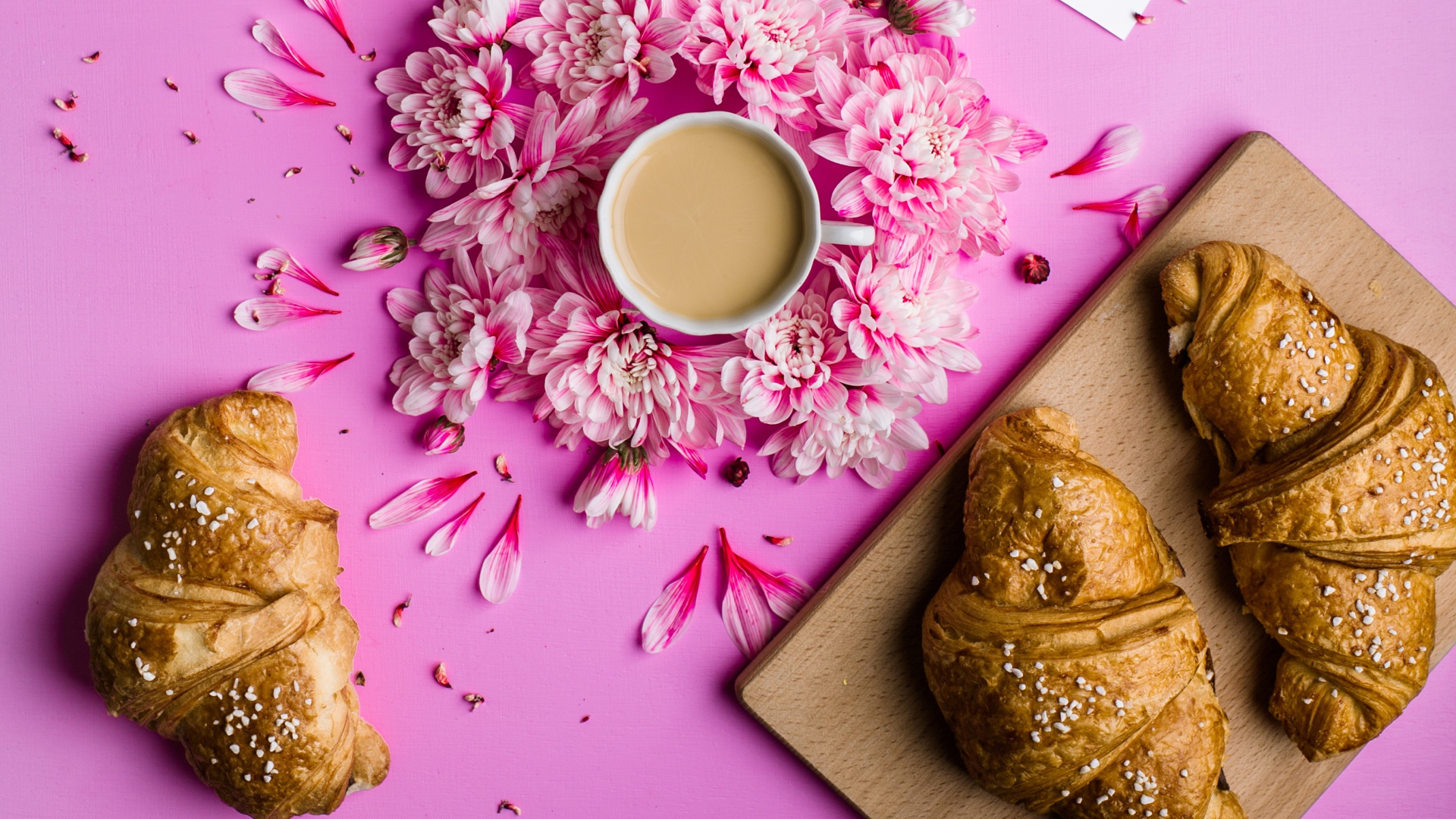 Свежие круассаны на столе с чашкой какао и цветами хризантемы