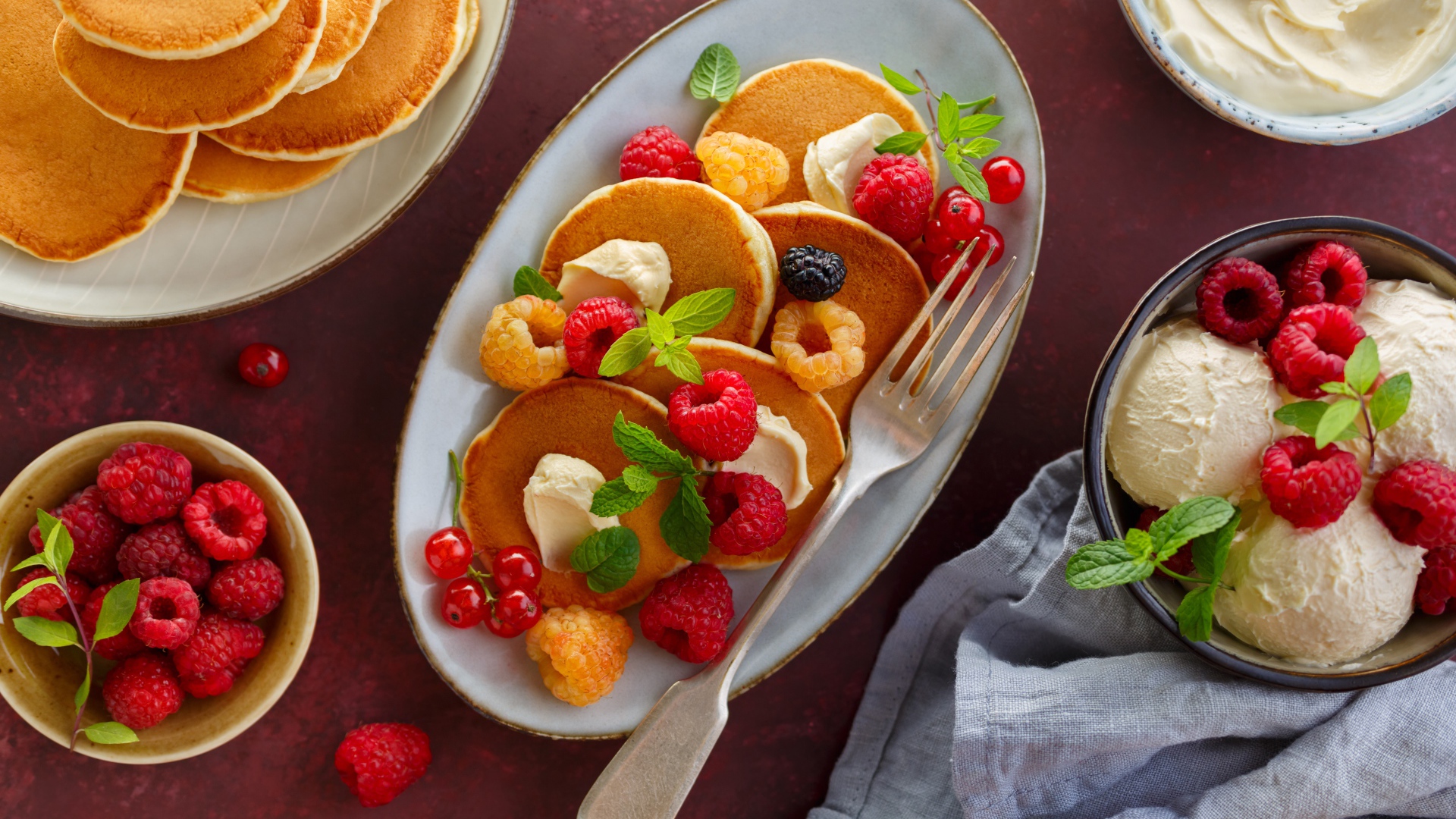 Оладьи на столе с ягодами малины и мороженым