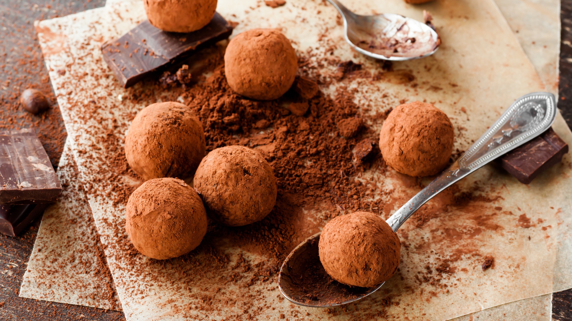 Круглые шоколадные конфеты в какао на столе с ложками